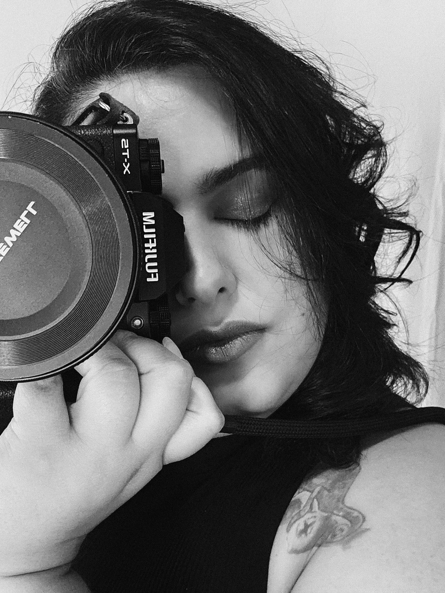 Black and white portrait of someone holding a camera to their face.
