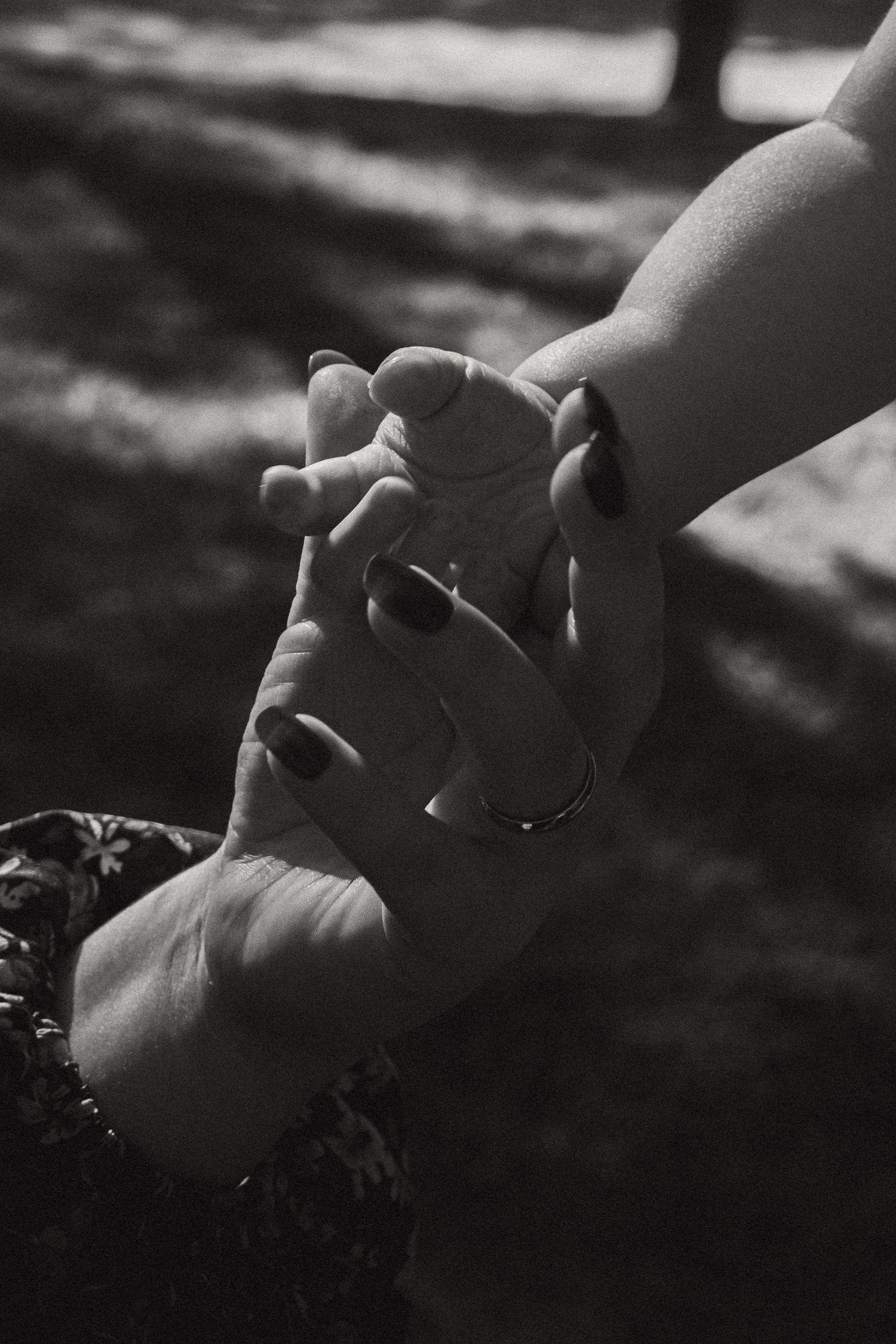 Close-up black and white image of two hands tenderly holding each other.