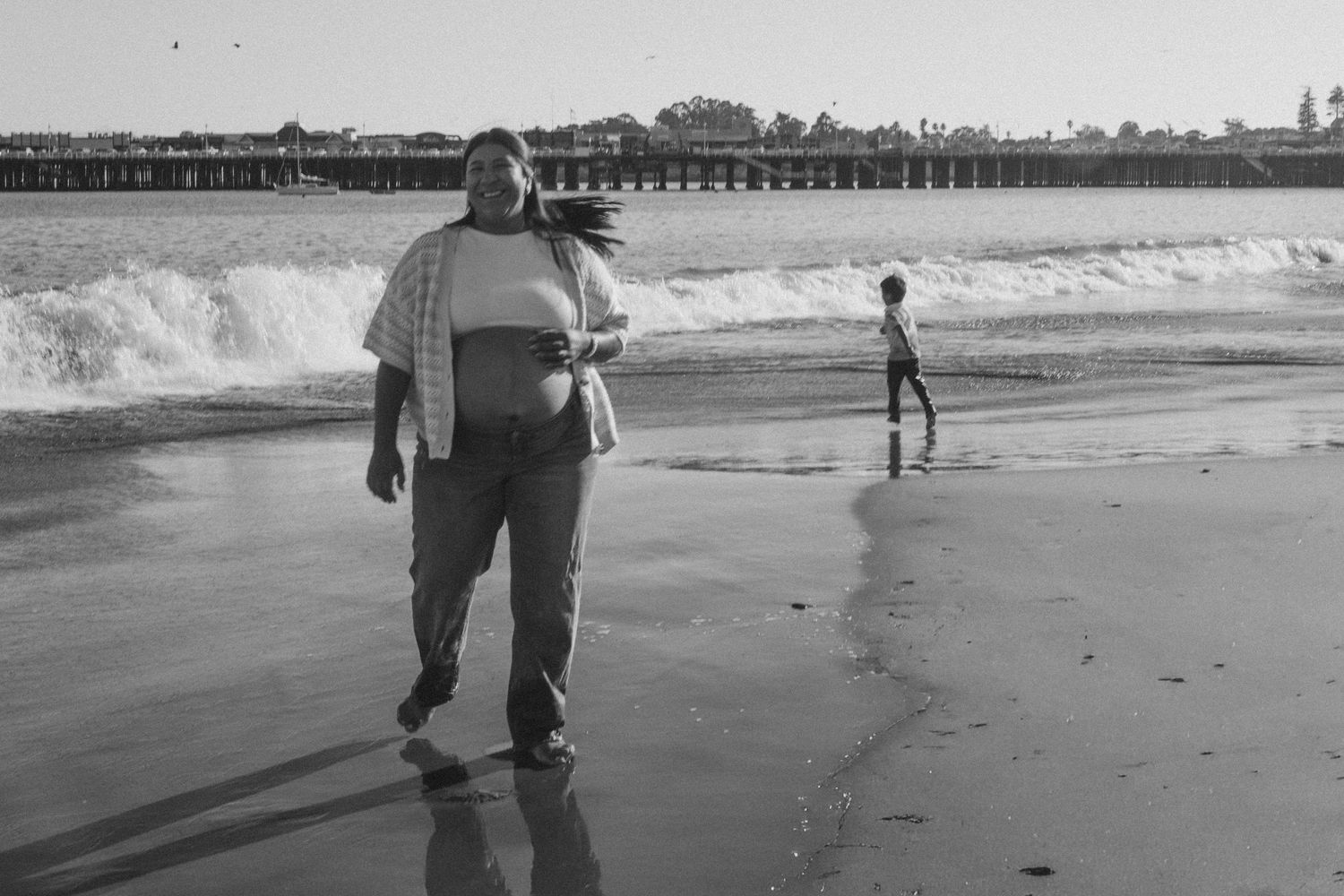 People walking along the shoreline of a beach with waves crashing nearby.