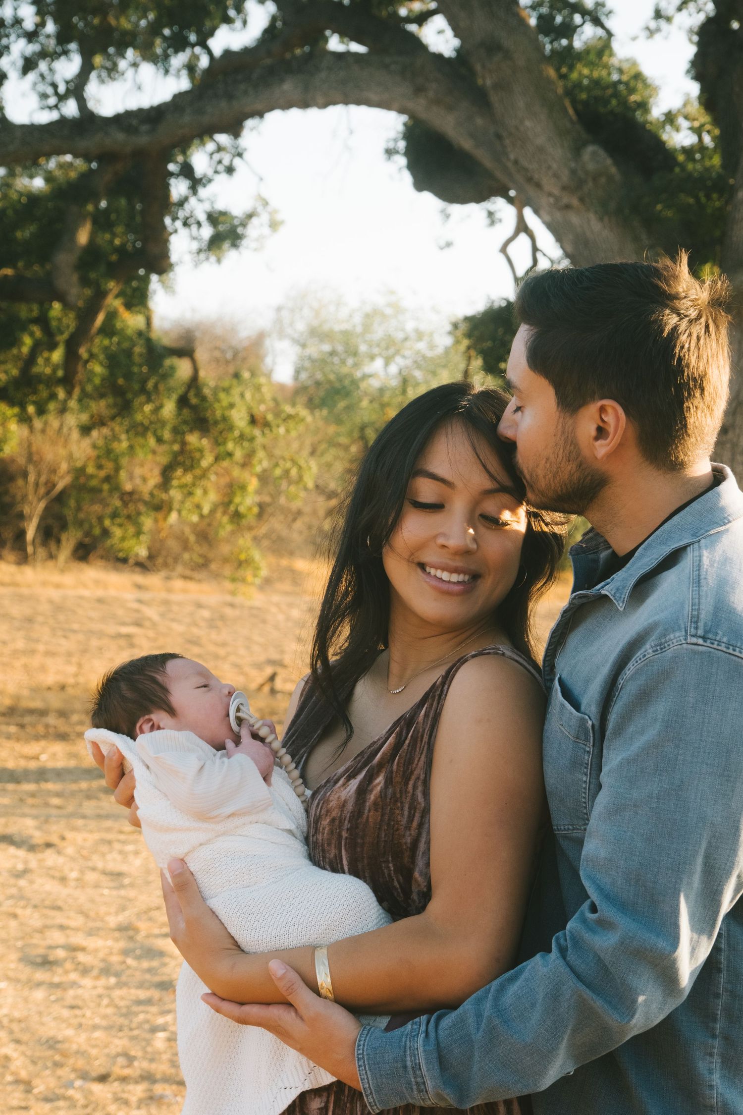 Family embraces during sunset photo session under trees.