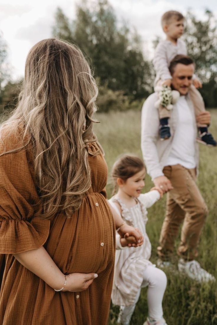 Family enjoying outdoor moment in grassy field during maternity photoshoot.