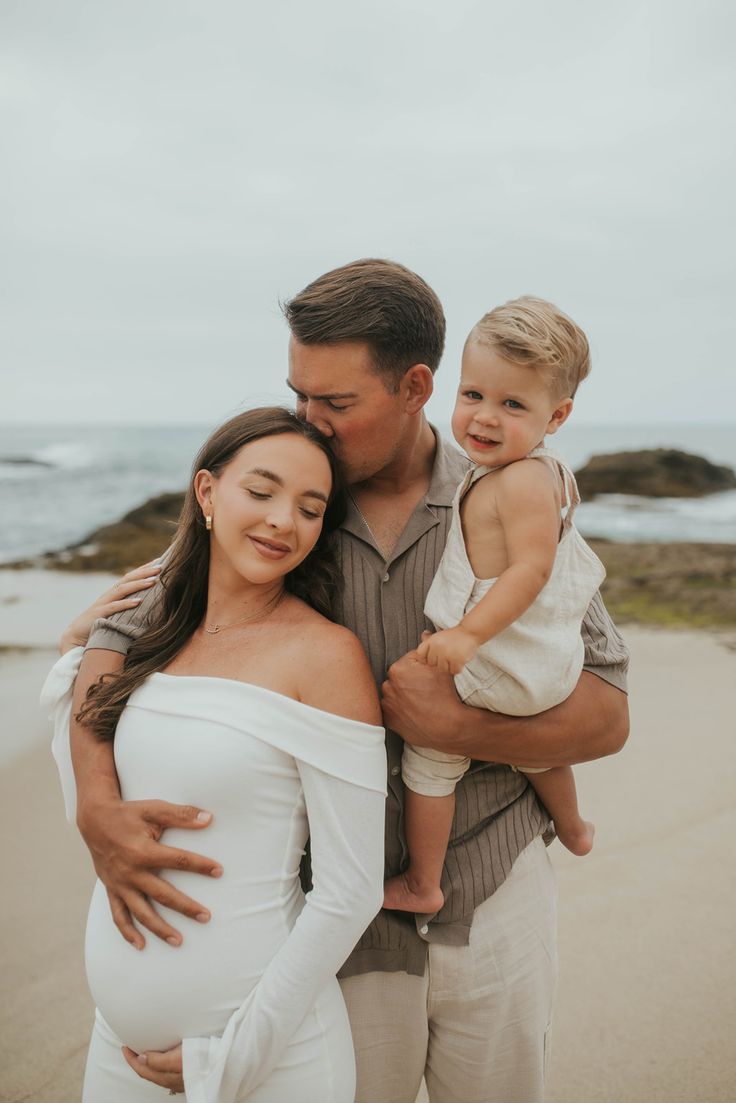 Family sharing tender moment on beach with young child.