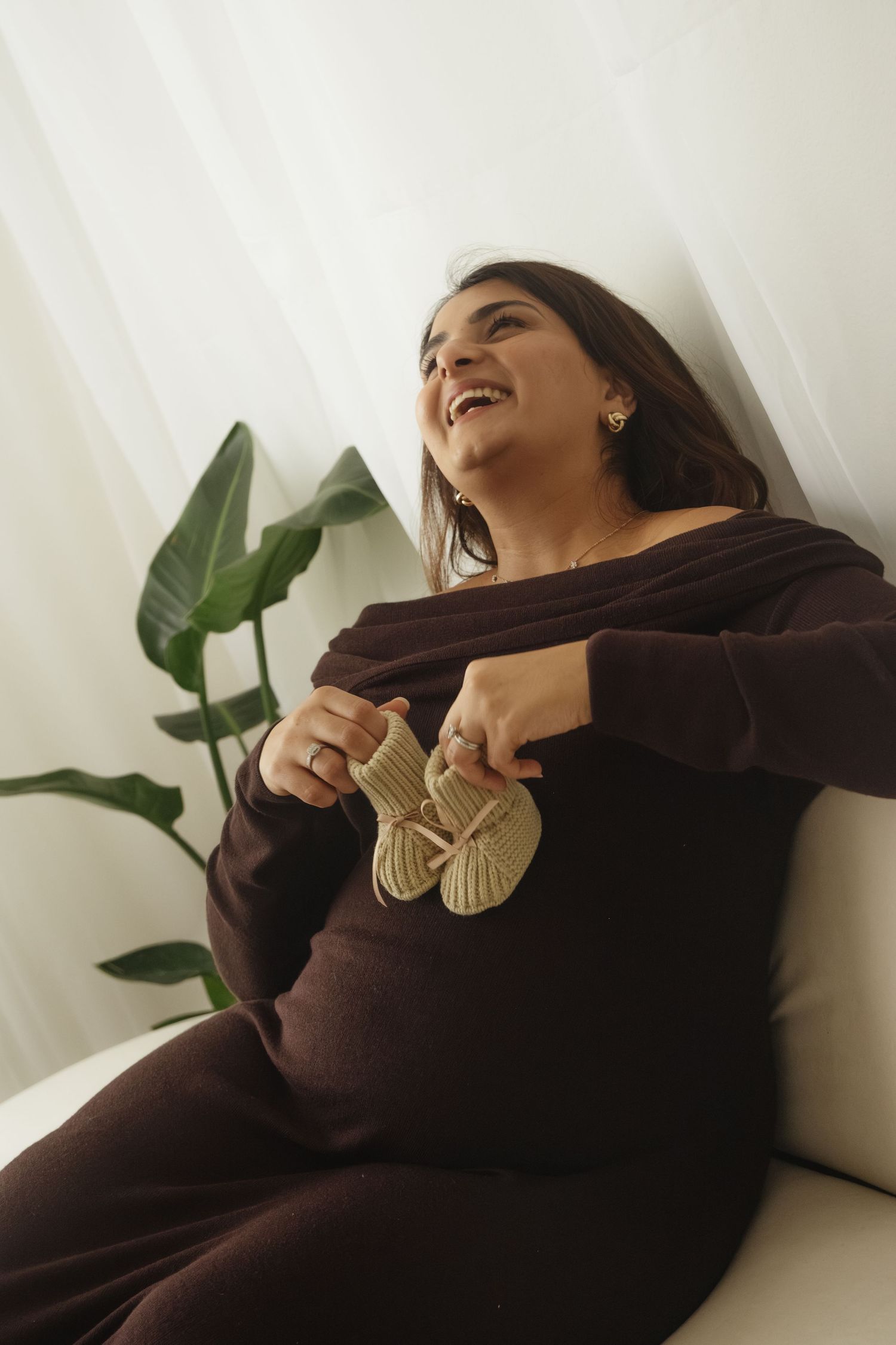 A pregnancy photoshoot featuring candid laughter and natural lighting.