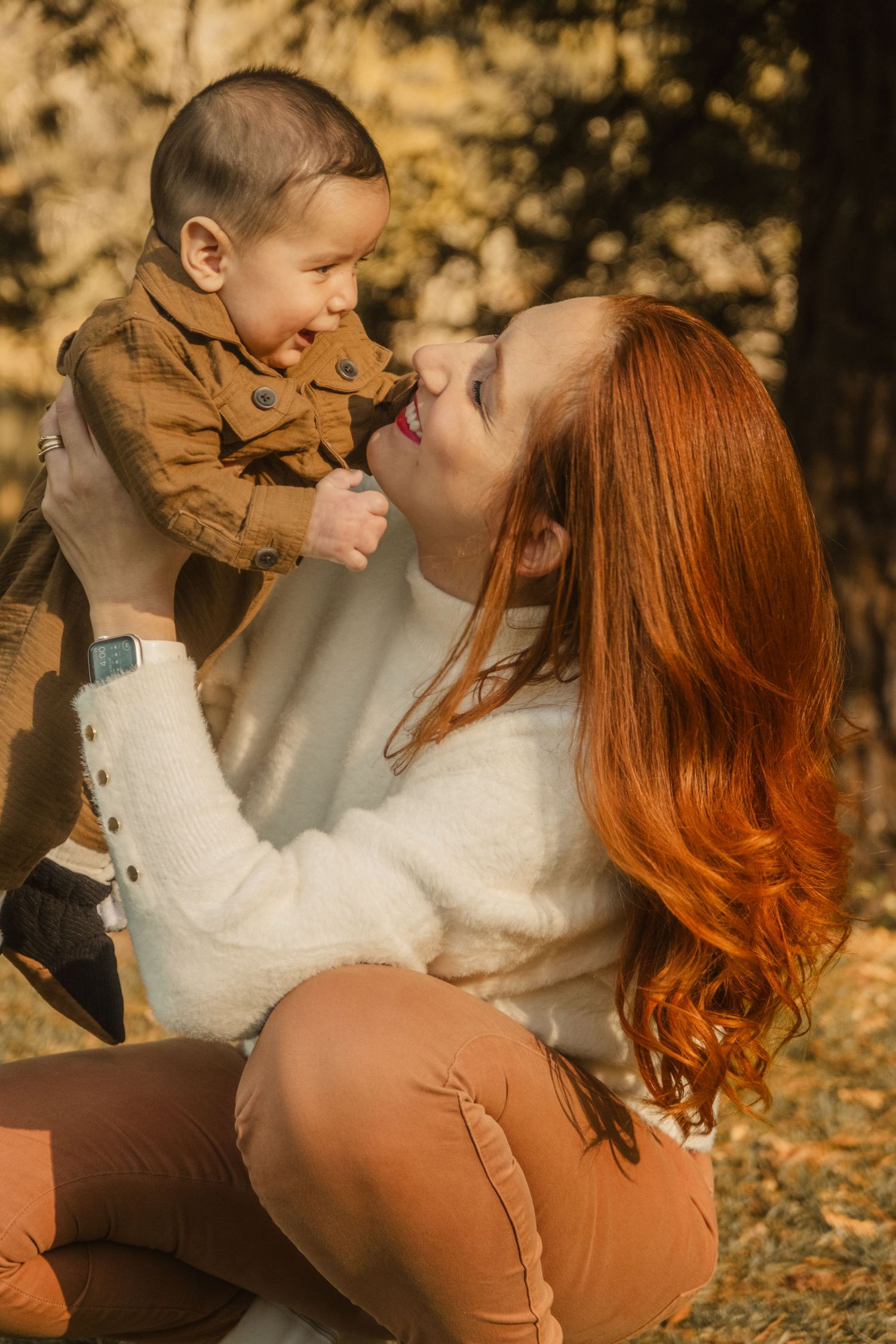 A tender autumn family moment captured in warm lighting among fallen leaves.