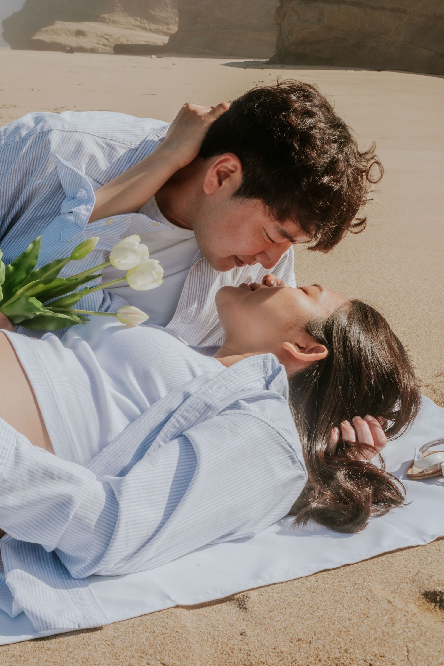 A romantic beach photoshoot with white tulips and soft natural lighting.