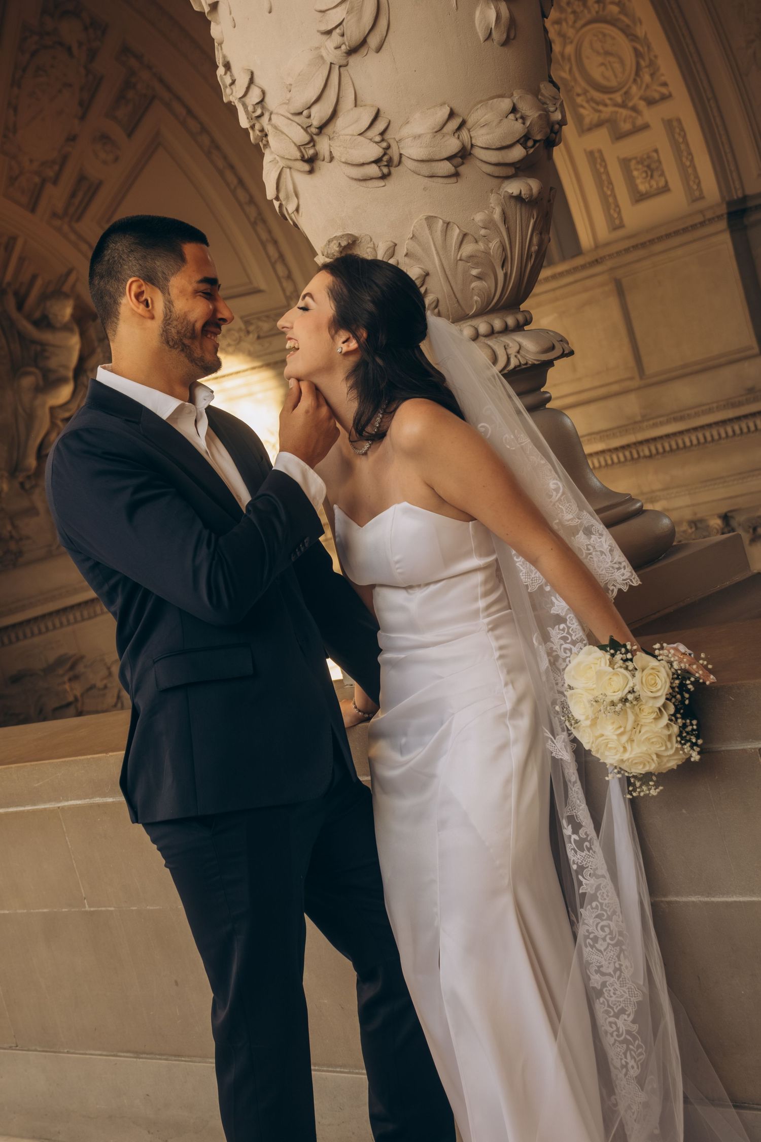 Couple shares romantic moments against ornate architectural details in a historic building.