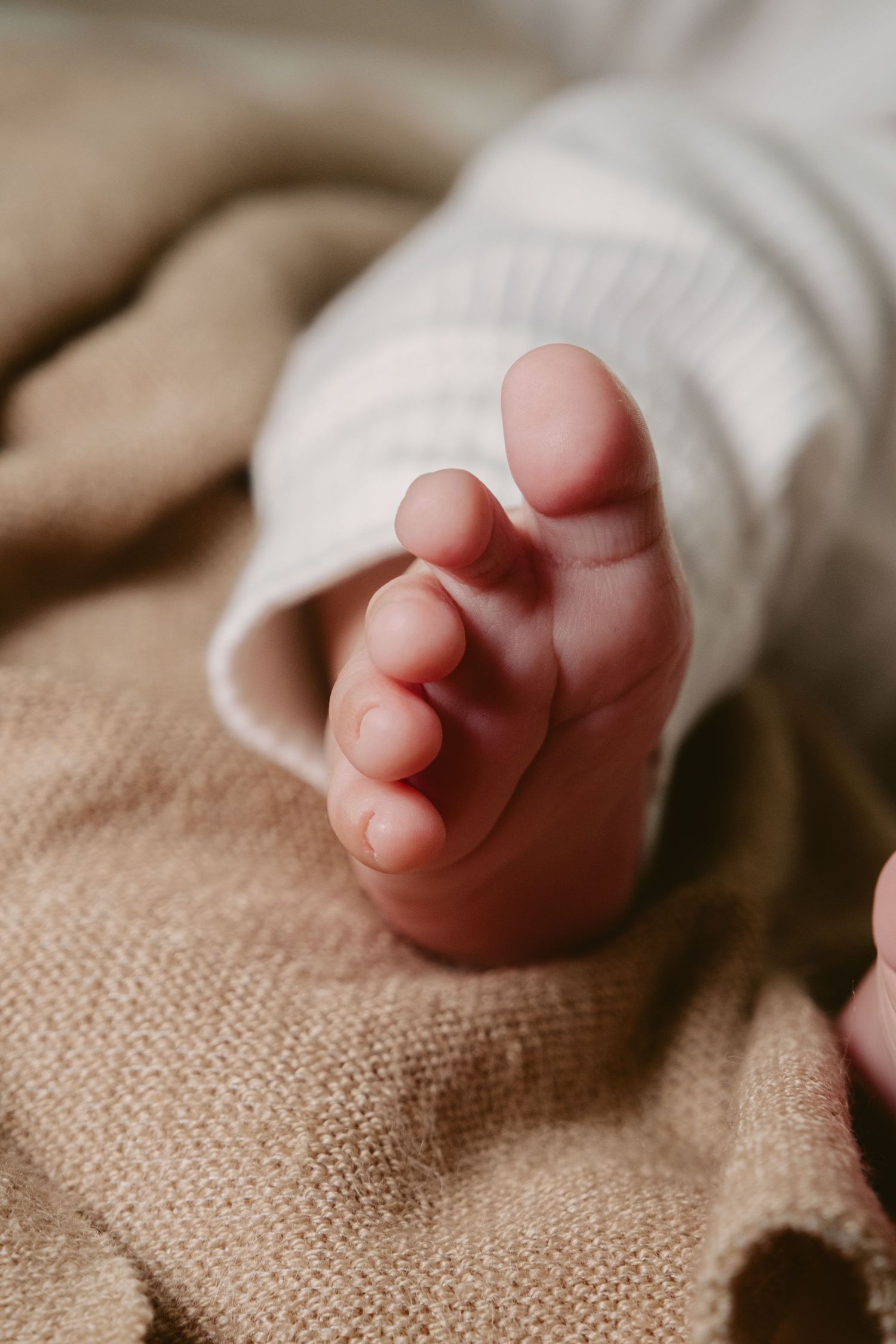 Close-up of baby feet resting on beige textured fabric.