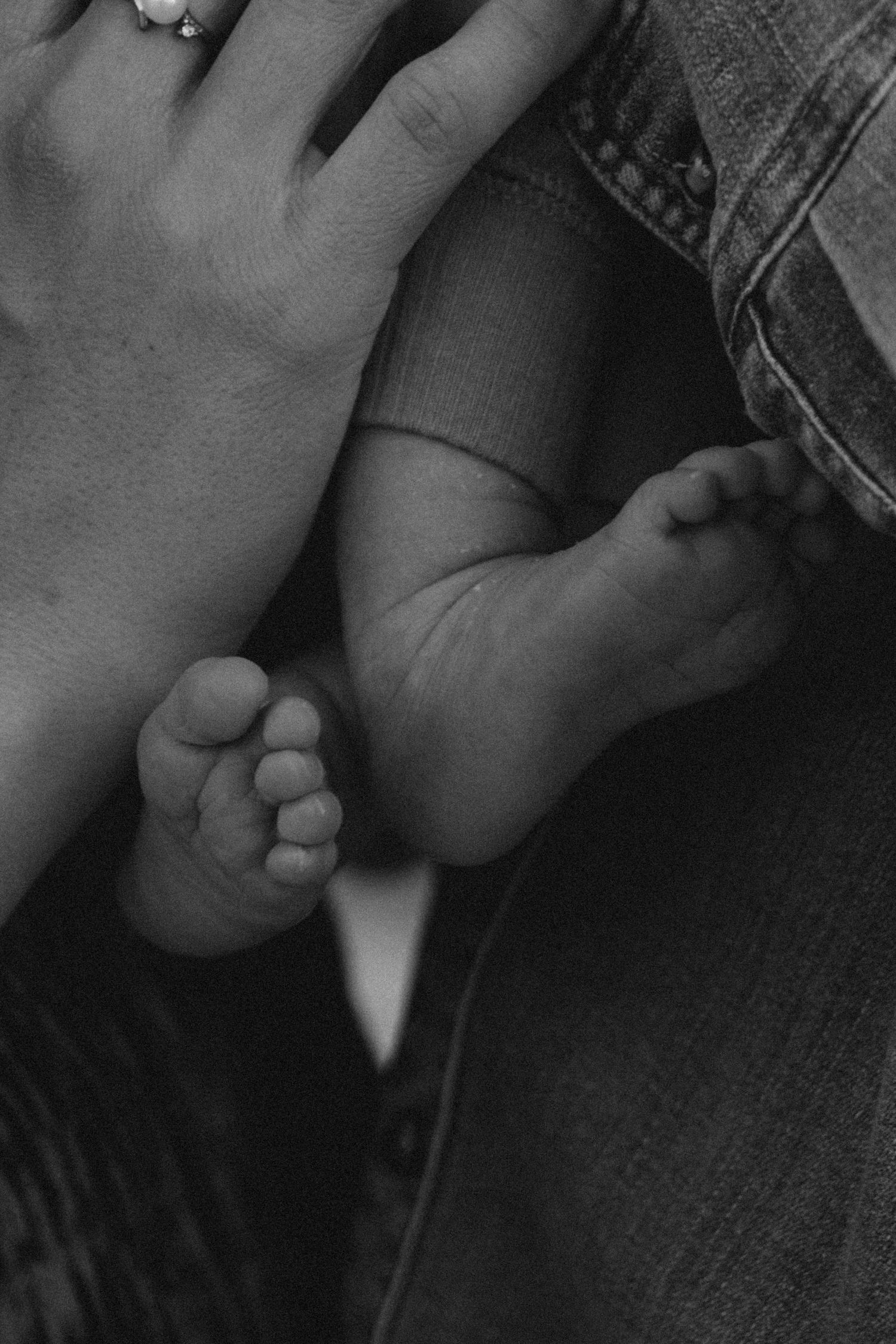 Black and white close-up sequence of tiny baby feet against denim fabric.