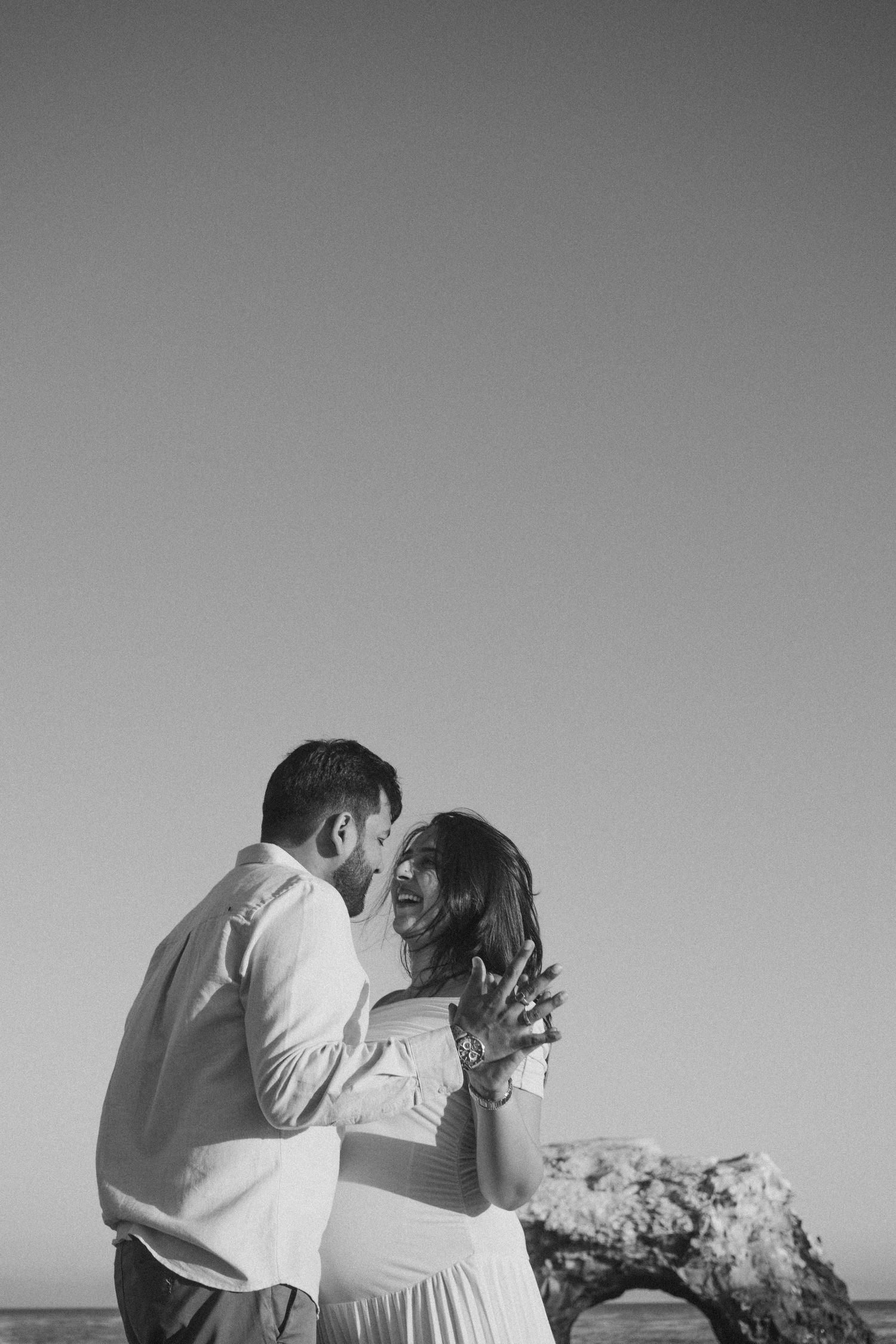 A couple embraces on the beach during a black and white photoshoot.