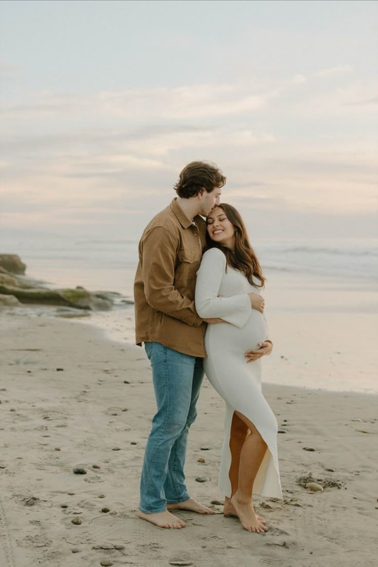 Romantic couple embracing on sandy beach during sunset.