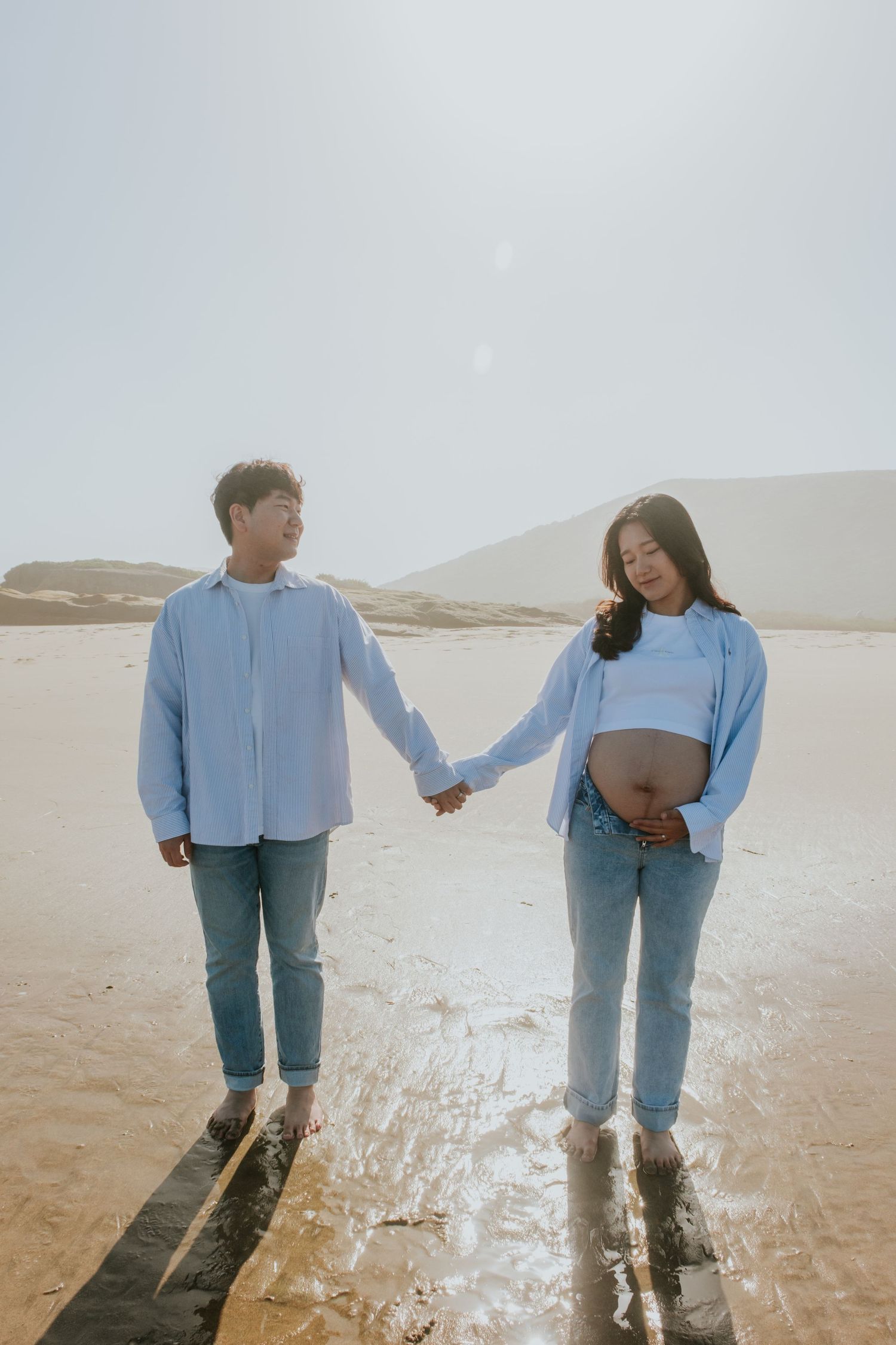 Couple in matching denim and blue shirts posing playfully on a salt flat landscape.