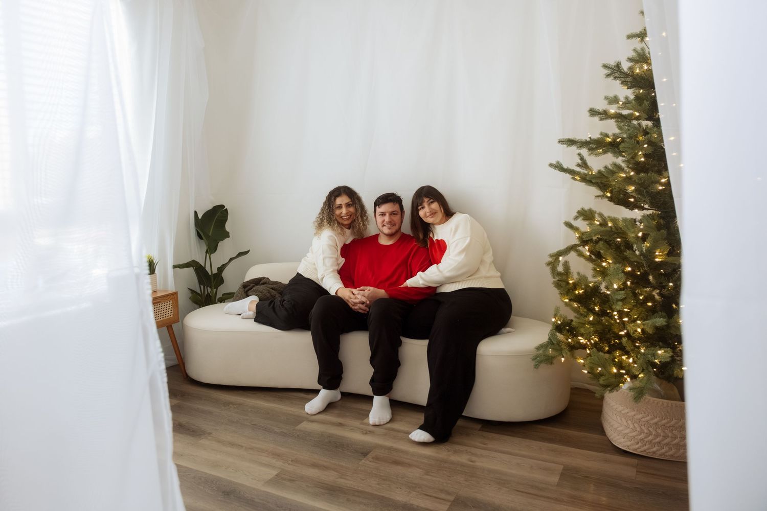 Candid moments captured on floor near decorated Christmas tree in bright indoor setting.