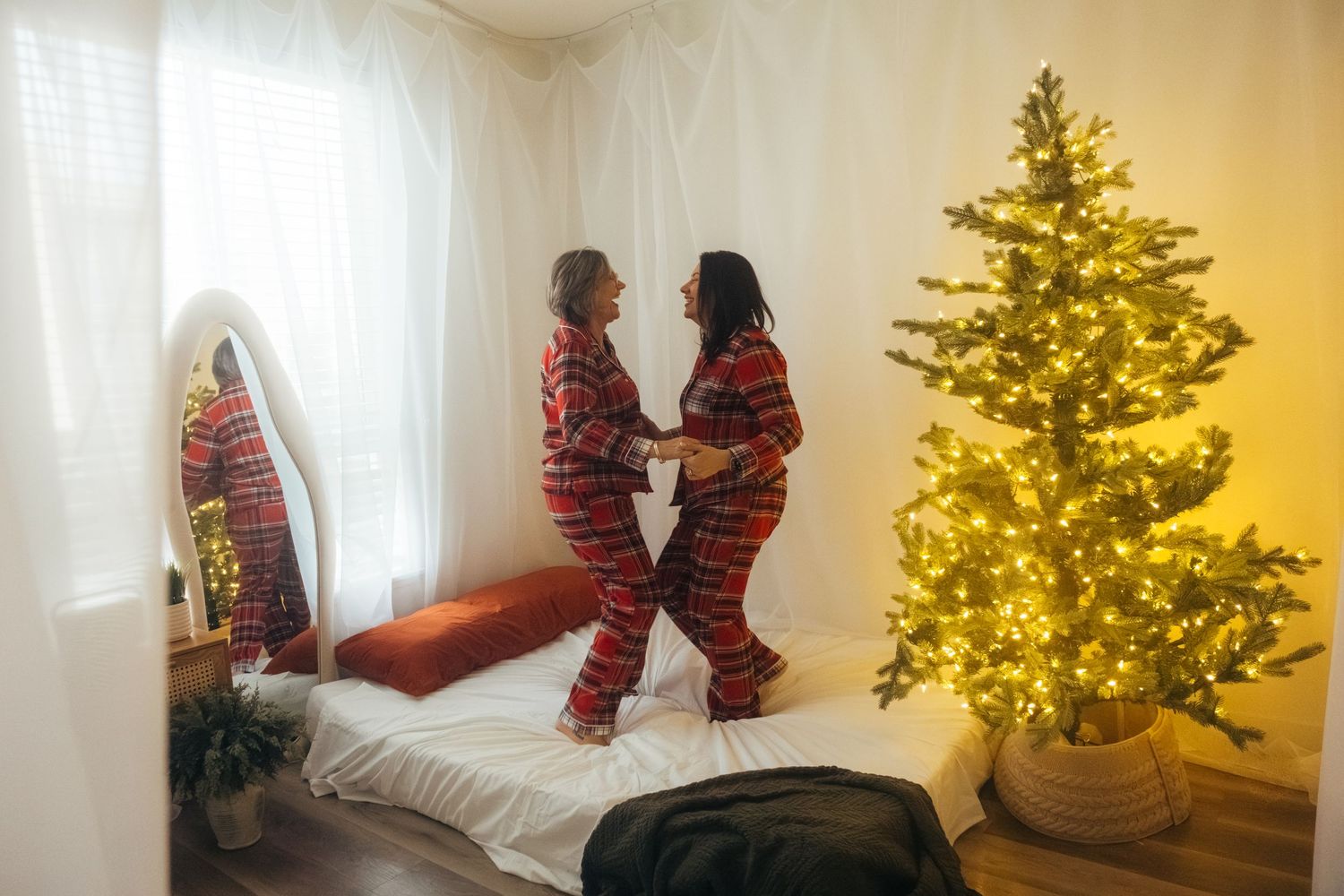 A decorated Christmas tree glows with warm lights in a cozy interior setting.