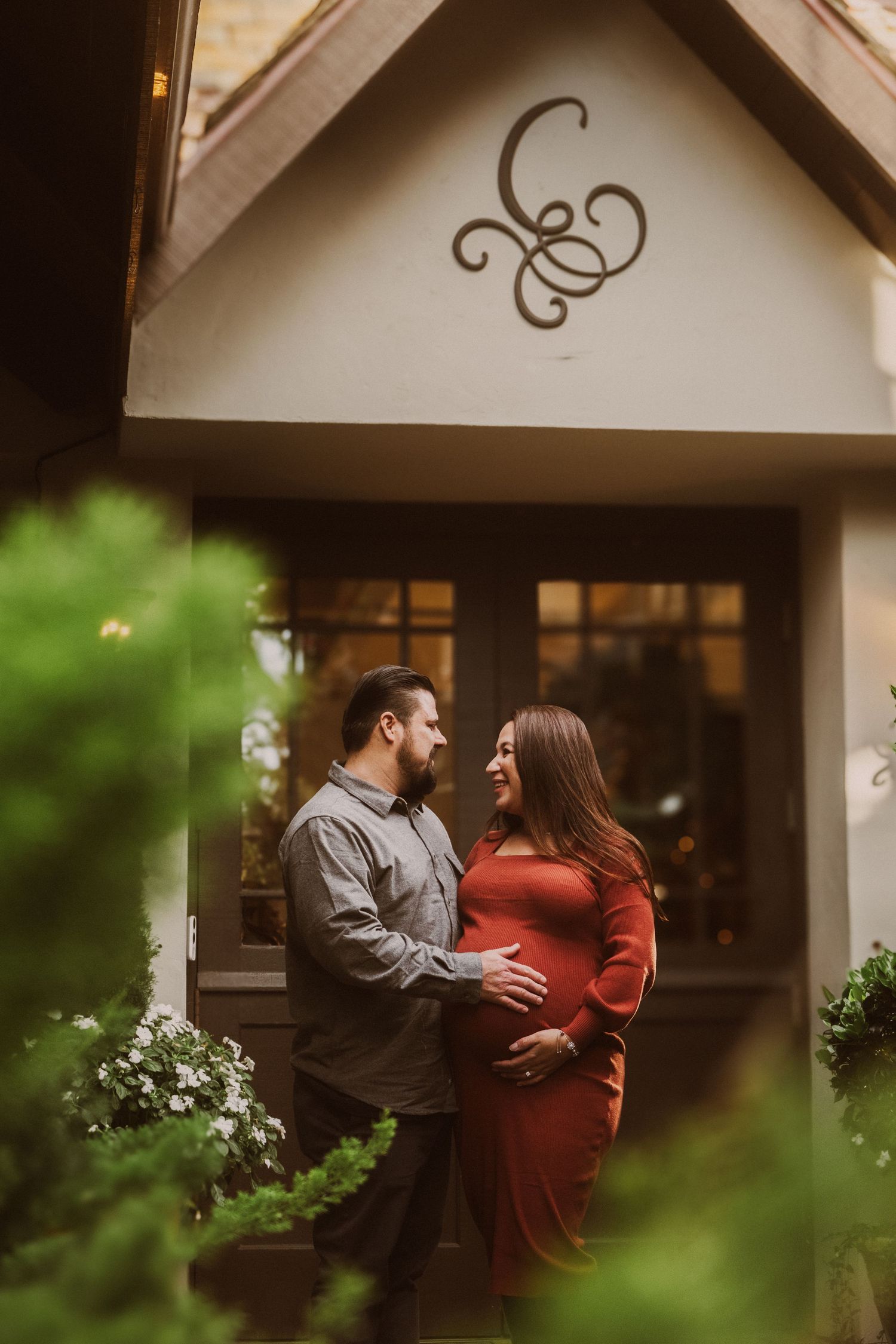 A romantic moment captured through foliage outside a building entrance.