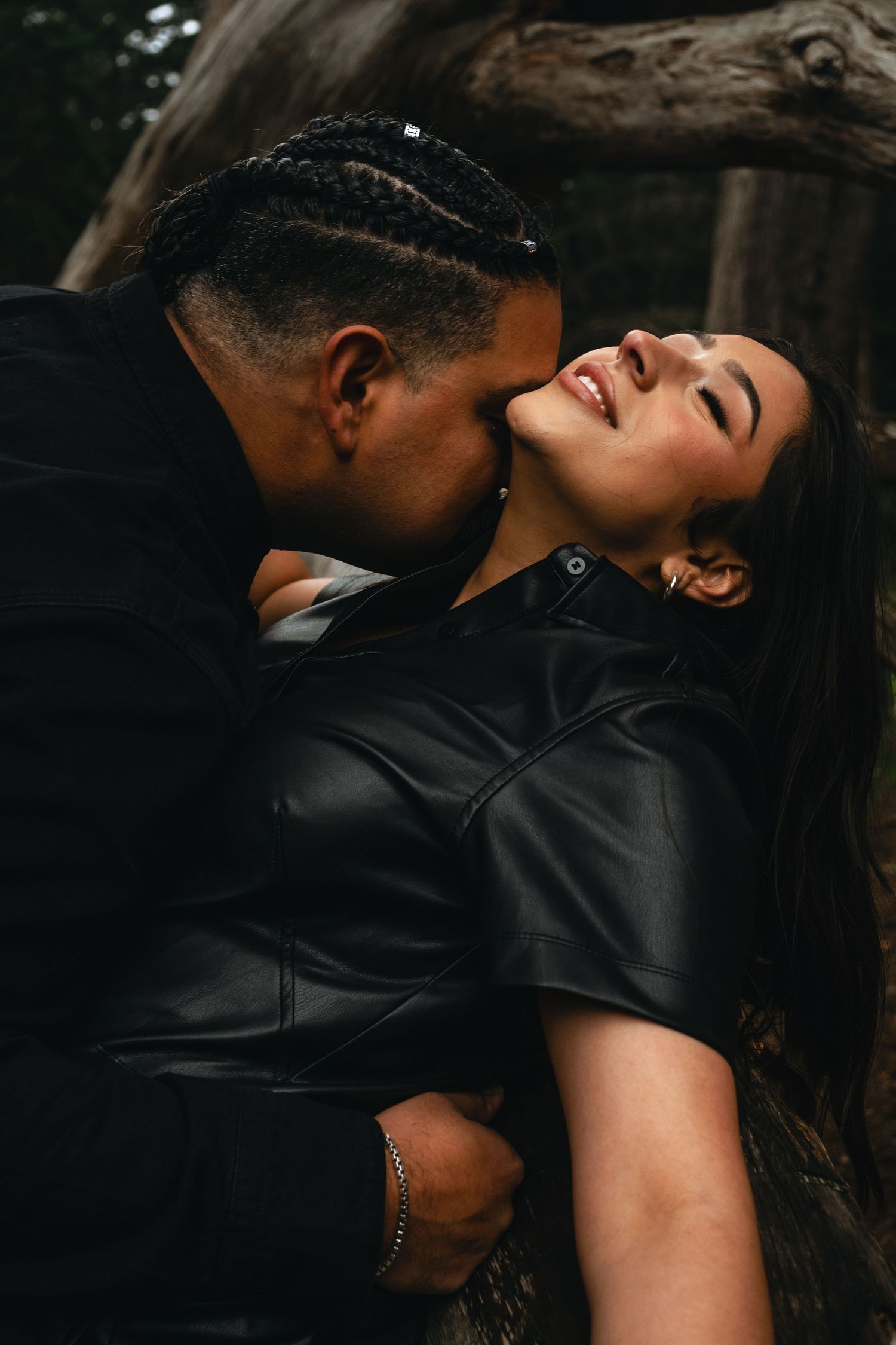 Intimate couple portrait in dark moody lighting wearing black clothing.