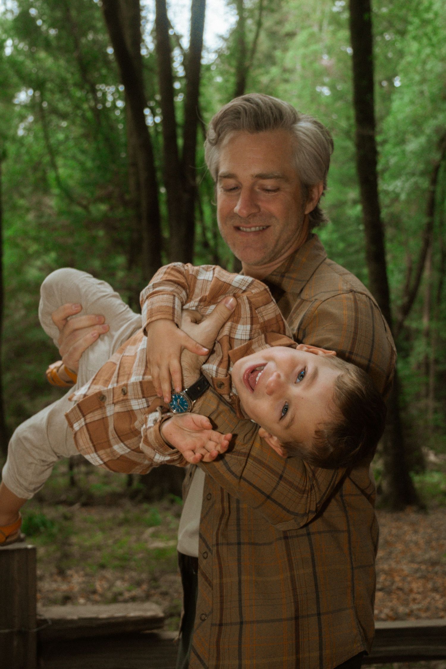 A tender moment shared between two people in a sunlit forest setting.