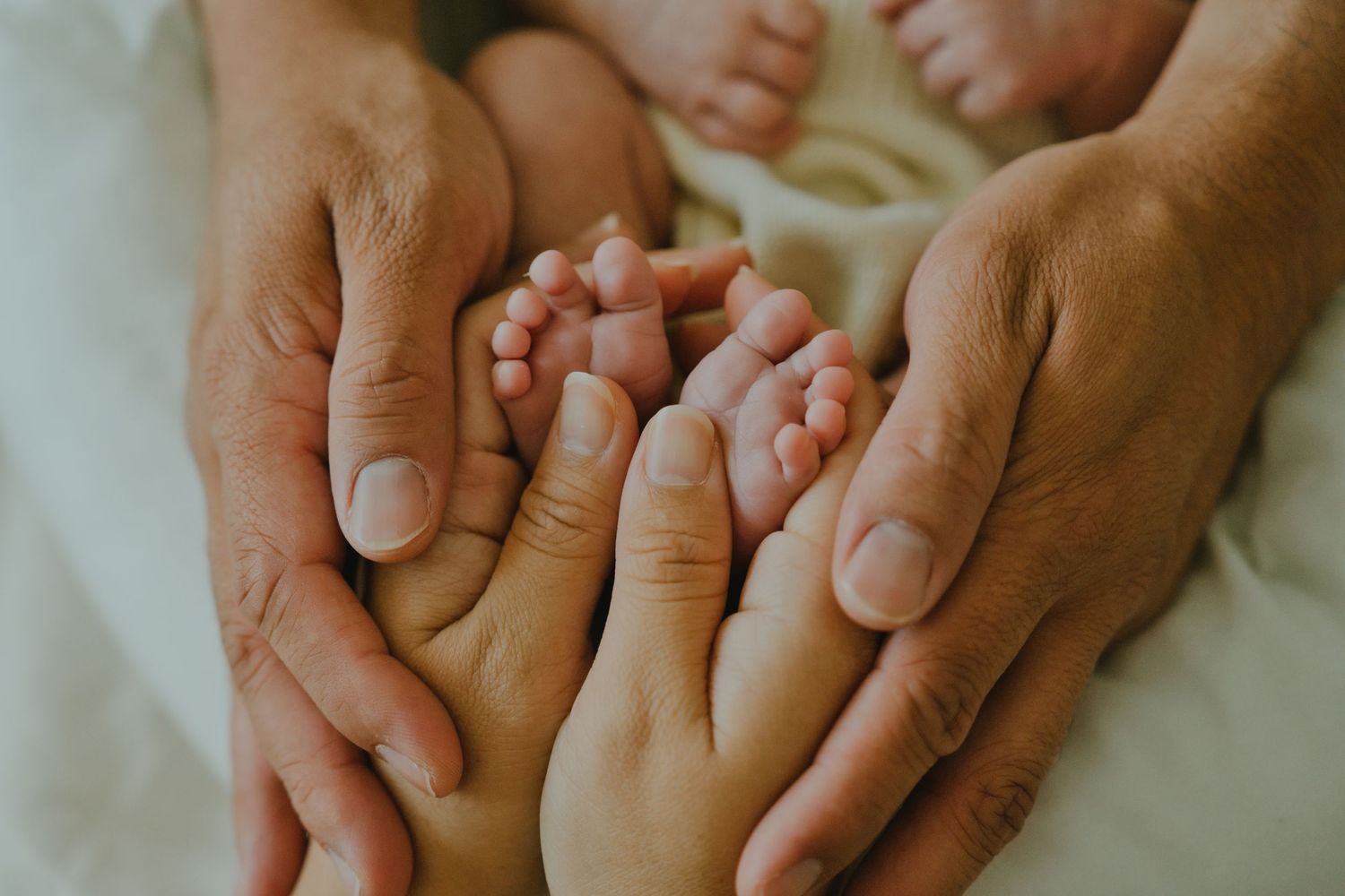 Adult hands gently cradling tiny newborn baby feet, symbolizing love and new parenthood.