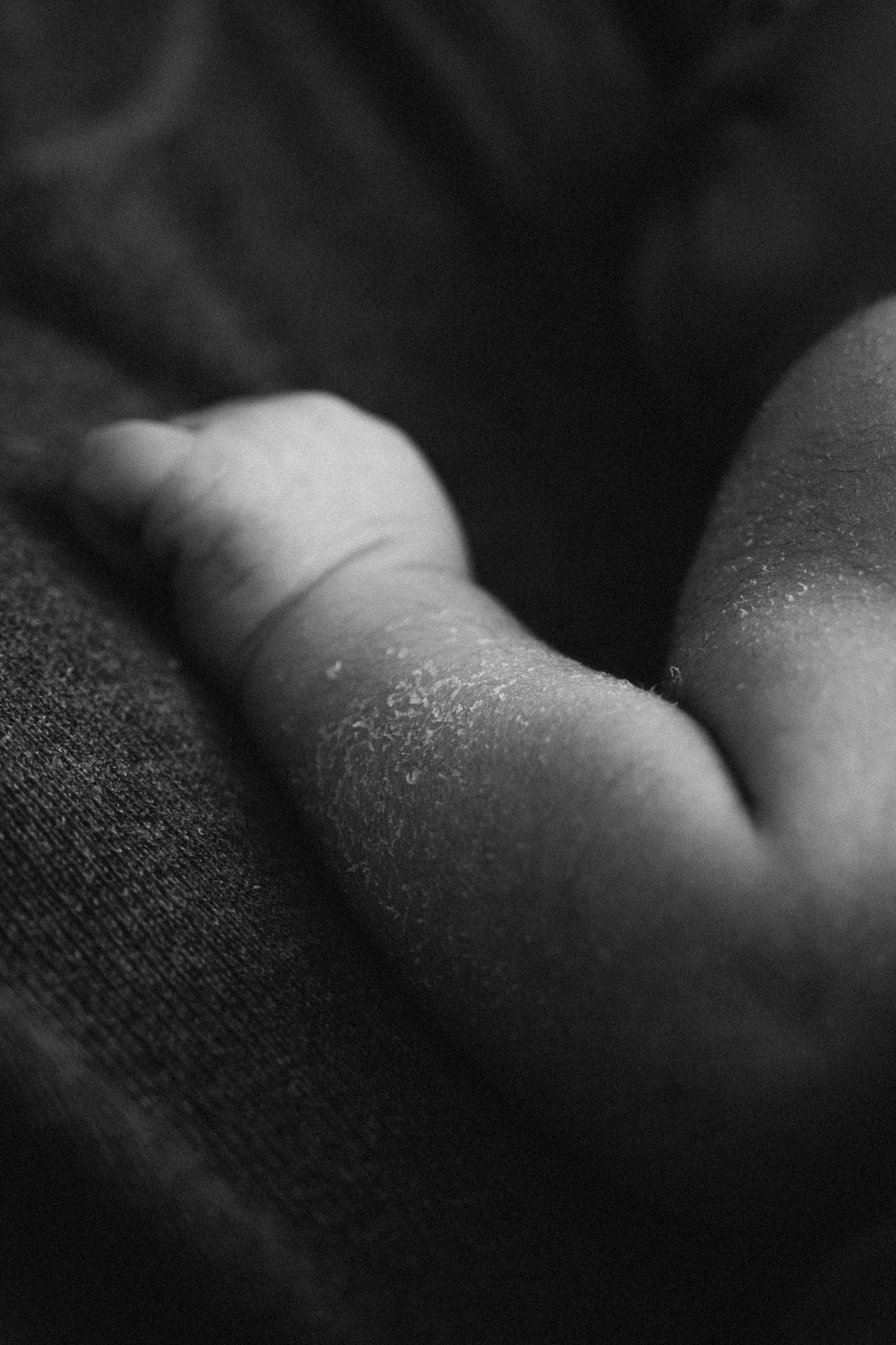 Black and white macro shot of a baby's delicate skin against soft fabric.
