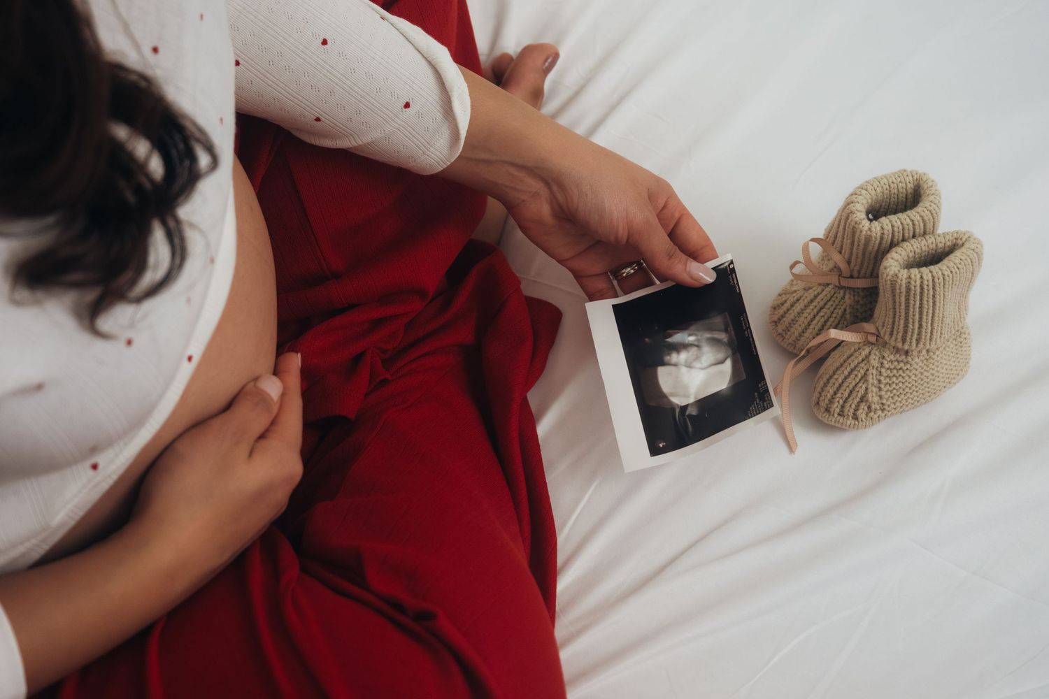 Intimate couple sharing tender moments while holding ultrasound photos.