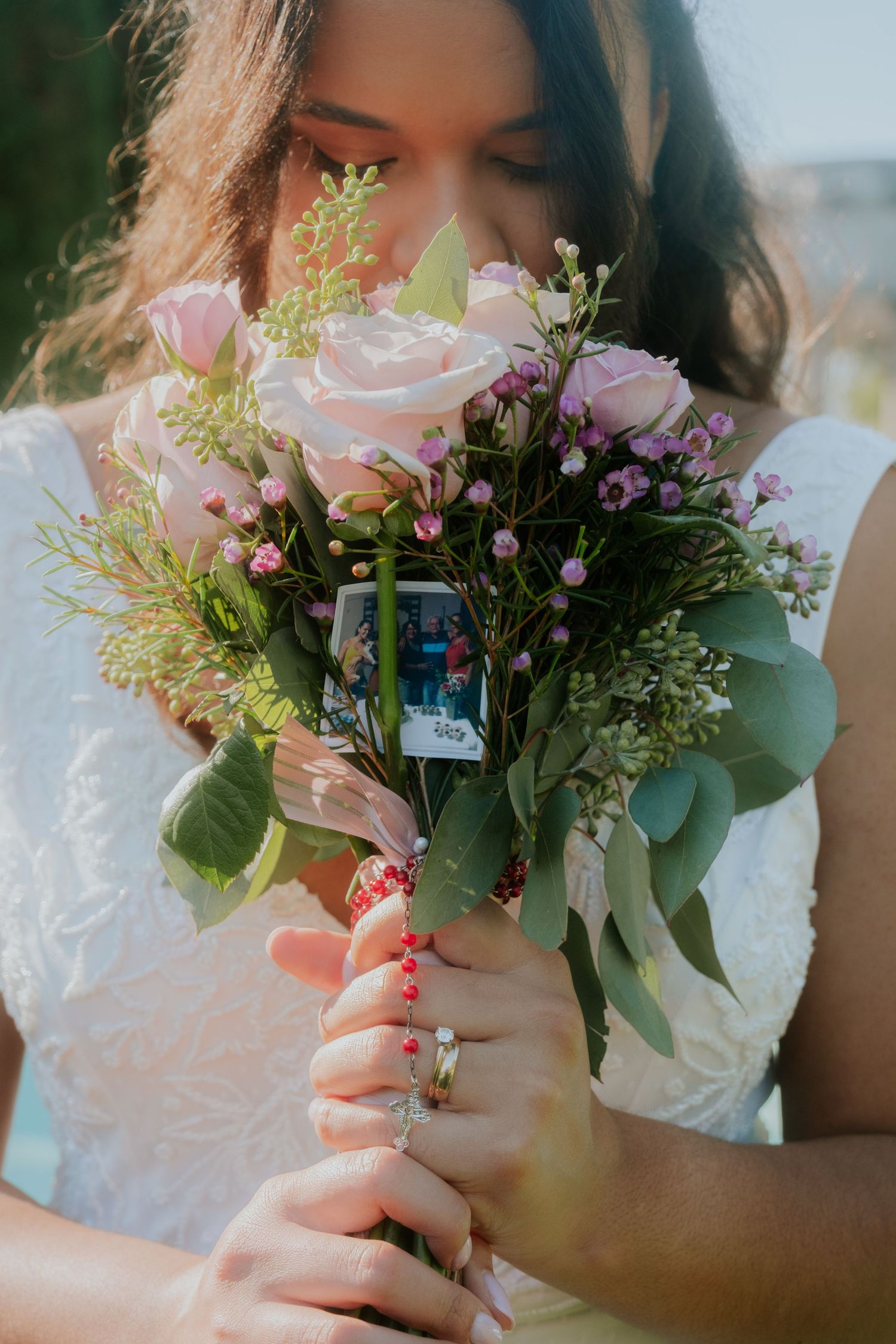 Close-up of bridal bouquet with pink roses, greenery and delicate white flowers.