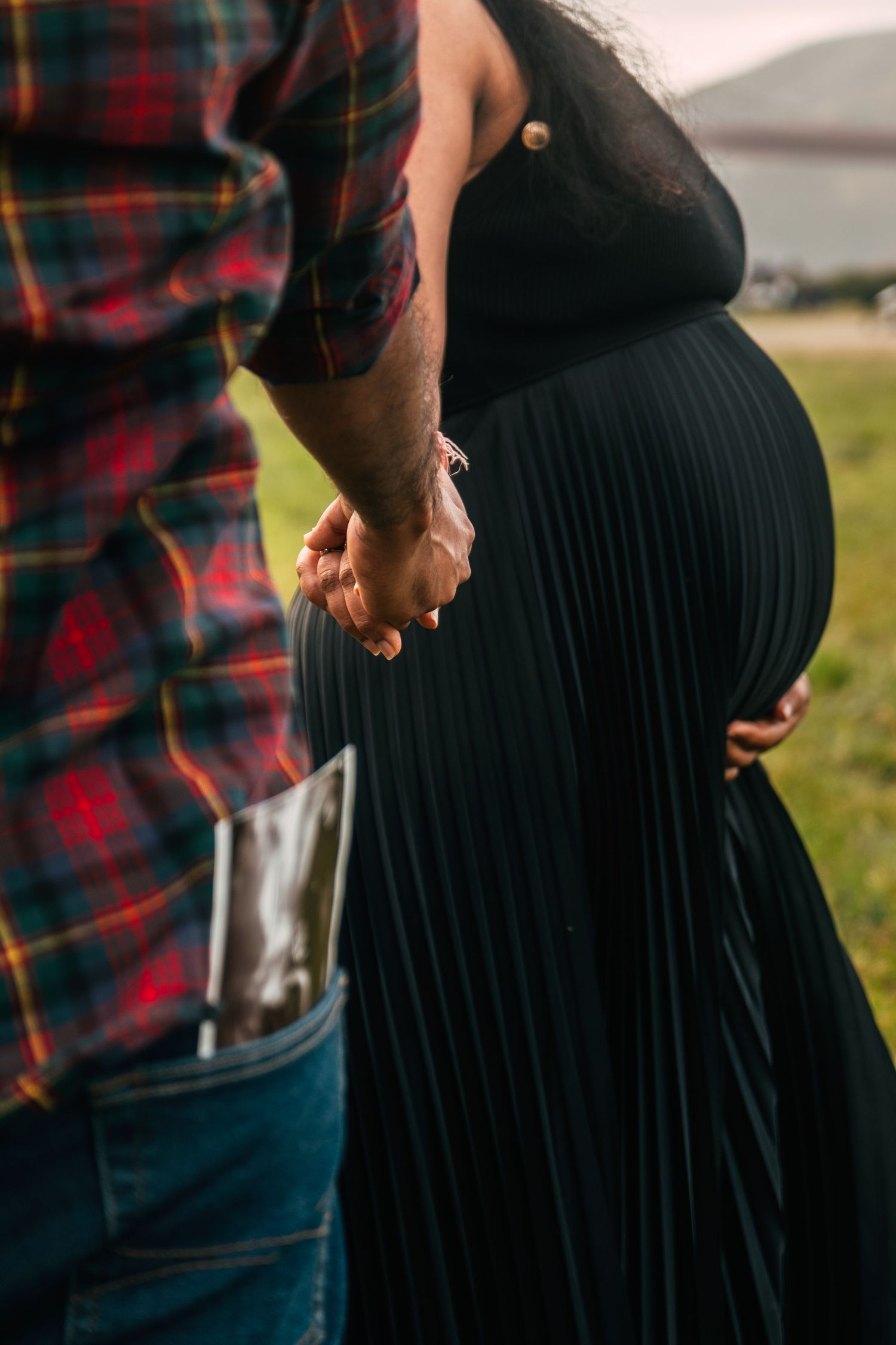 Close-up of couple holding hands in casual attire.