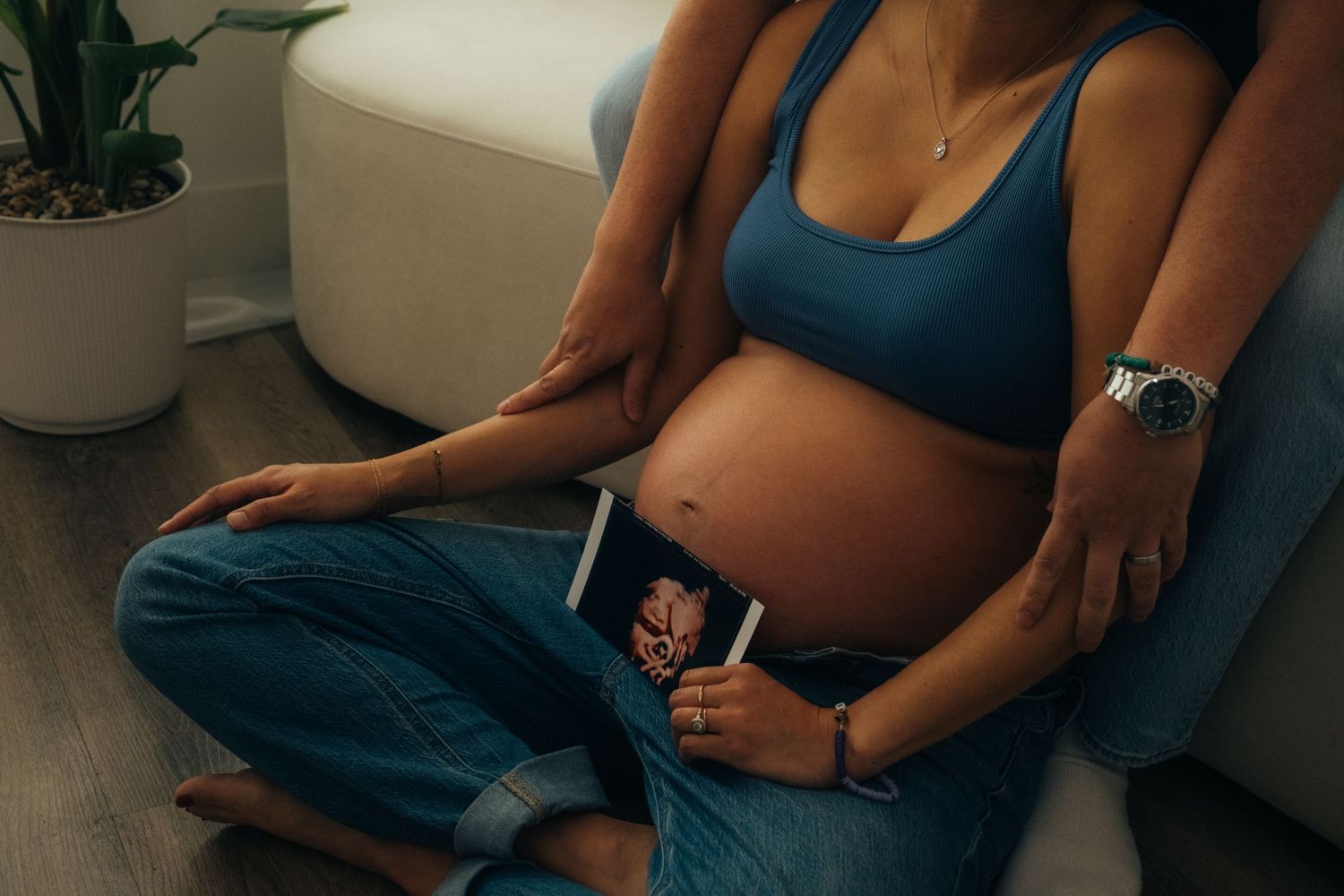 Casual pregnancy portrait session on couch with natural window lighting.