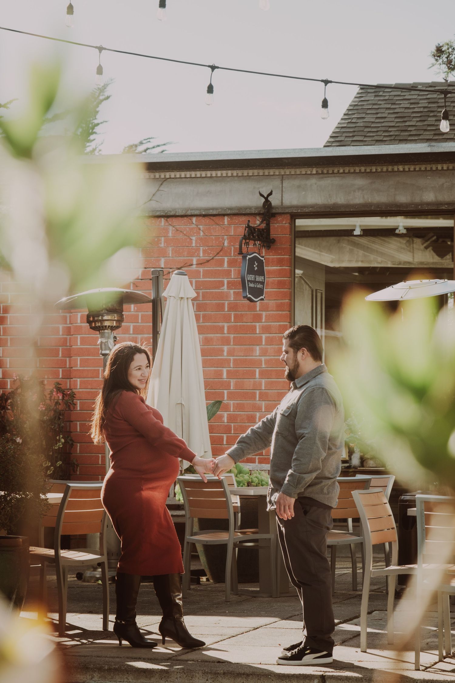 A couple shares a playful moment on an outdoor patio with brick walls.
