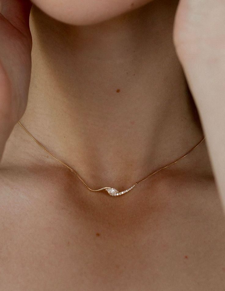 Close-up of a delicate gold chain necklace worn around a neck.