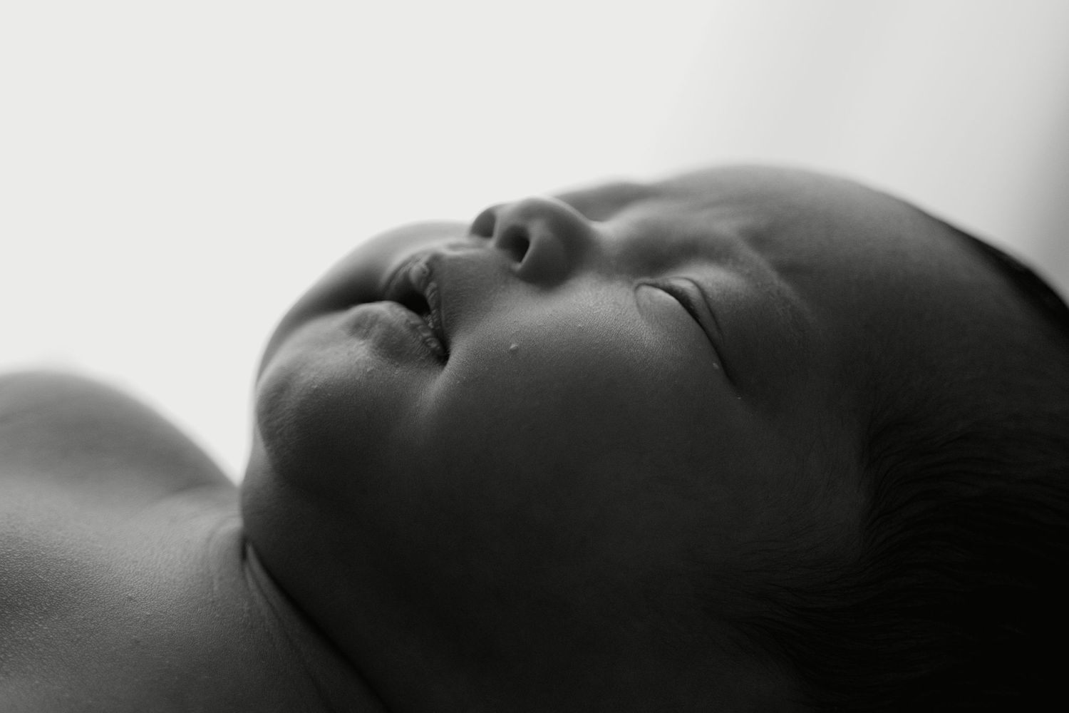 Close-up black and white portrait of a sleeping newborn baby with delicate features and soft skin.