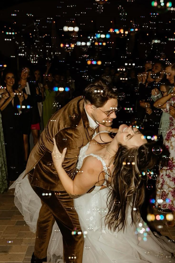 A romantic couple dances together at night with twinkling city lights glowing in the background.