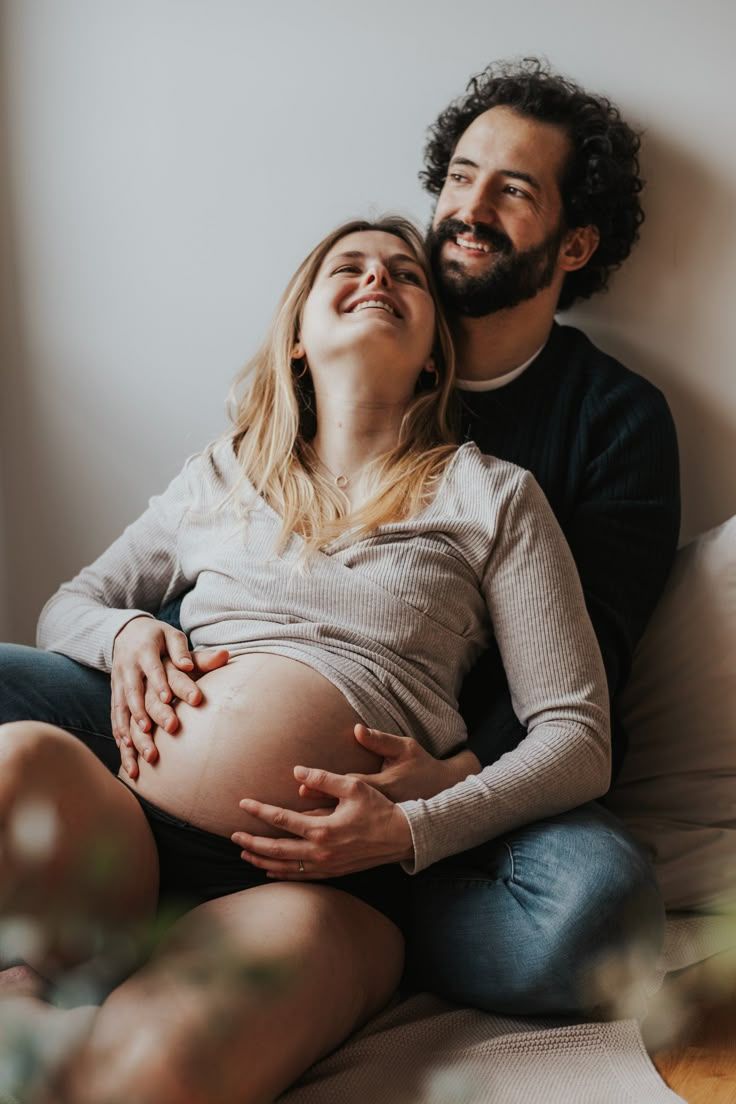 Cozy maternity session featuring couple sharing intimate moments on comfortable sofa.