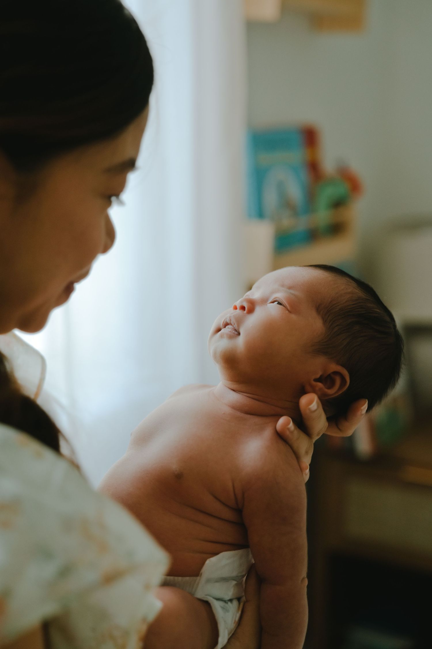 A mother tenderly holds her newborn baby in a warmly lit nursery room.