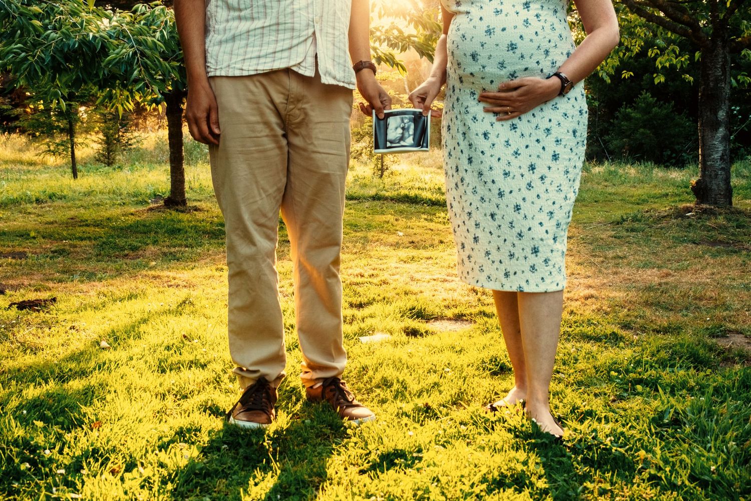 Couple embracing in golden afternoon sunlight on grassy field.