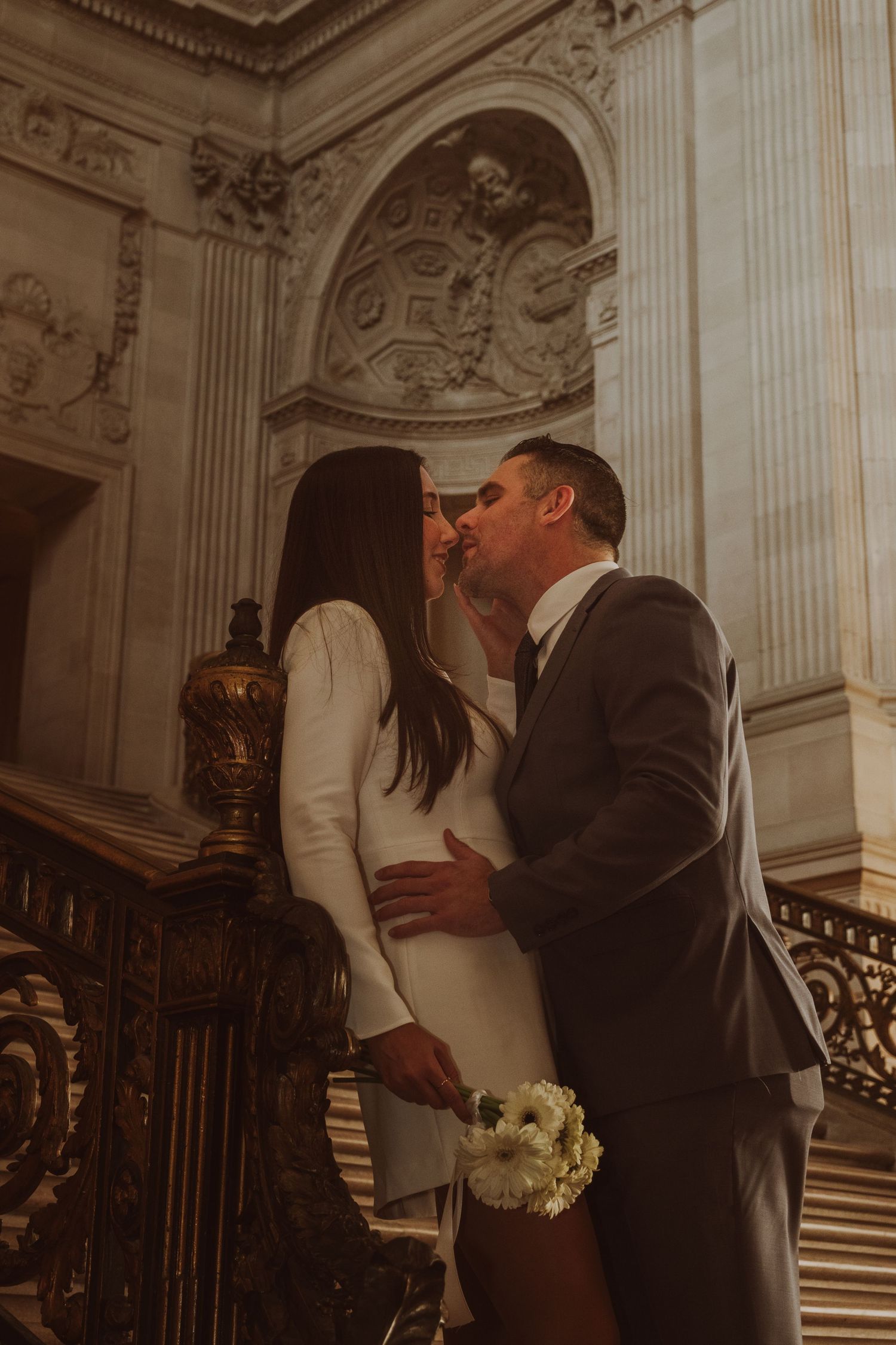 Elegant couple sharing intimate moment in ornate historic building interior.