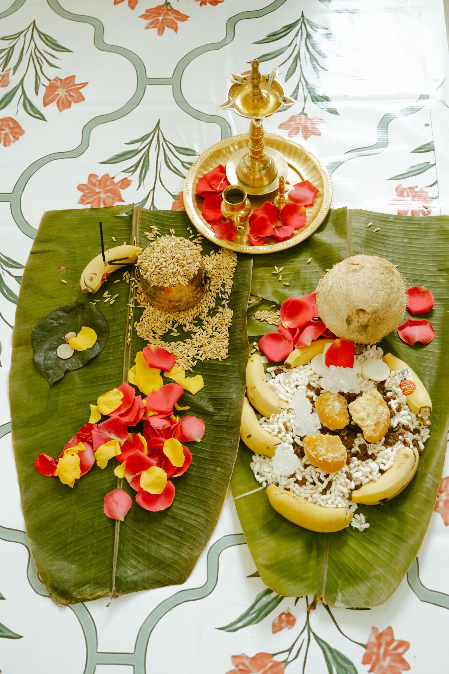Traditional South Indian banana leaf spread with rice, coconut, rose petals, and brass oil lamp for Hindu ritual ceremony.