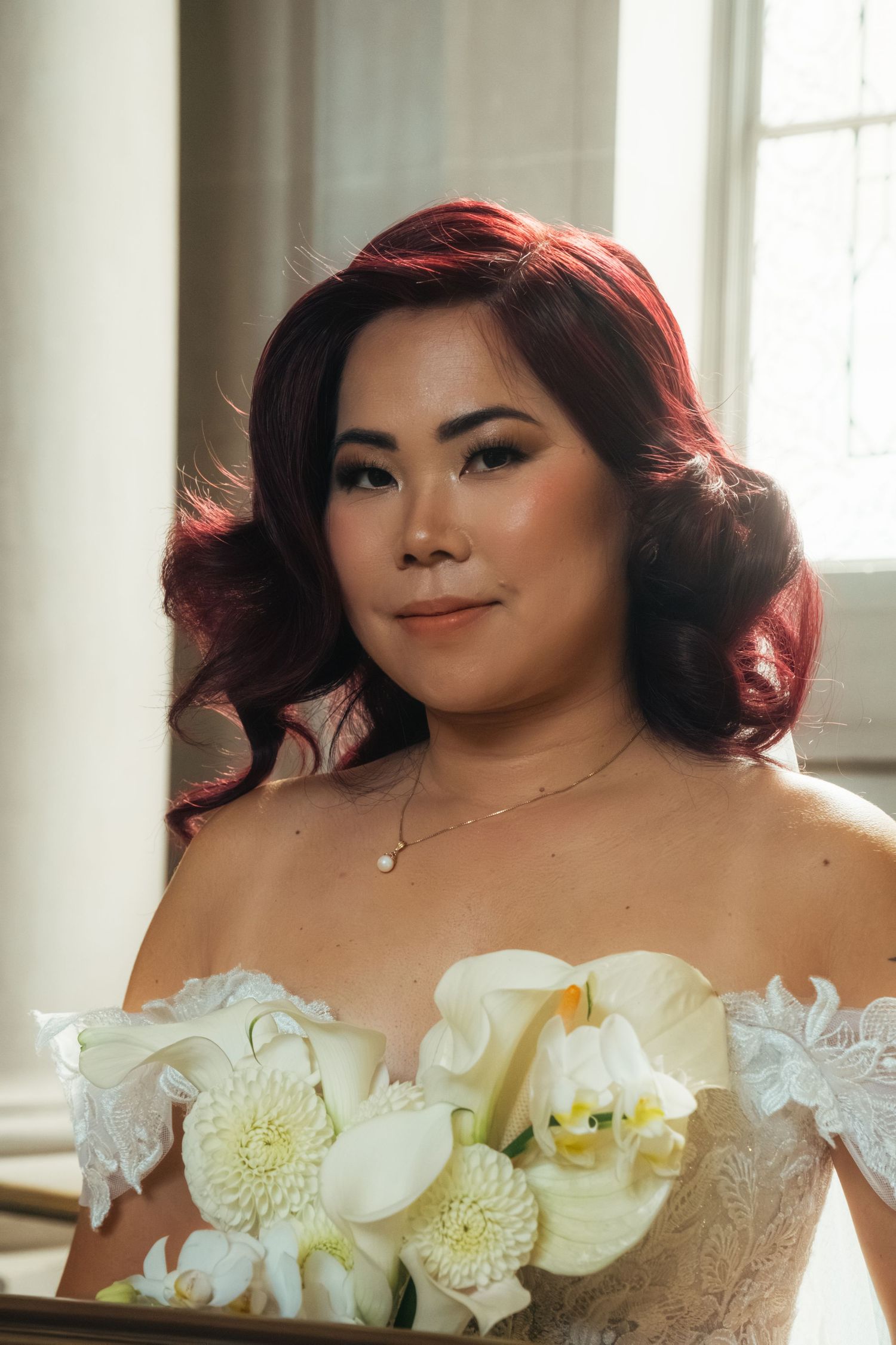 Bride wearing off-shoulder wedding gown with white orchid and dahlia floral details.