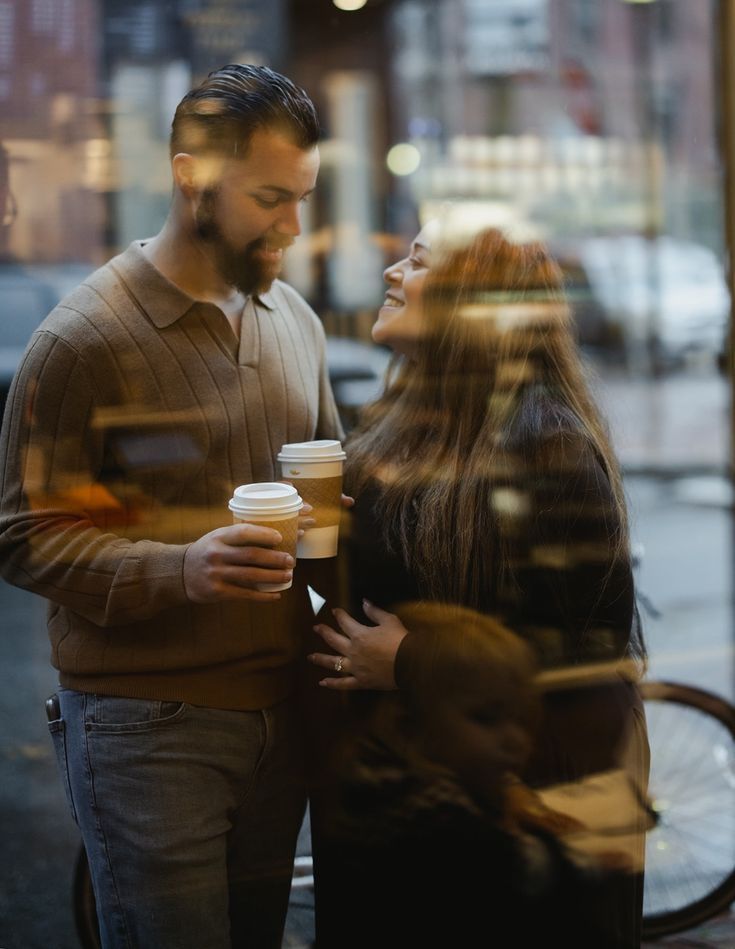Couple sharing intimate moments through cafe window reflections while having coffee.