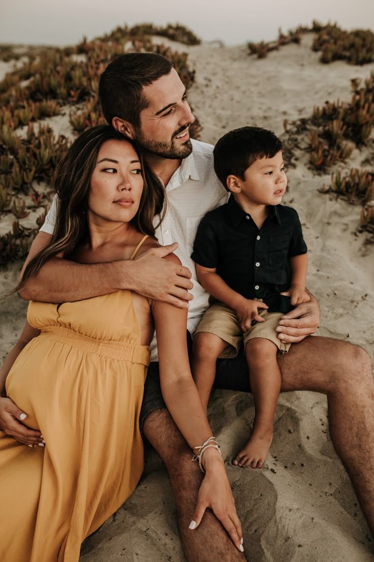 Family relaxing on sandy beach during golden hour.