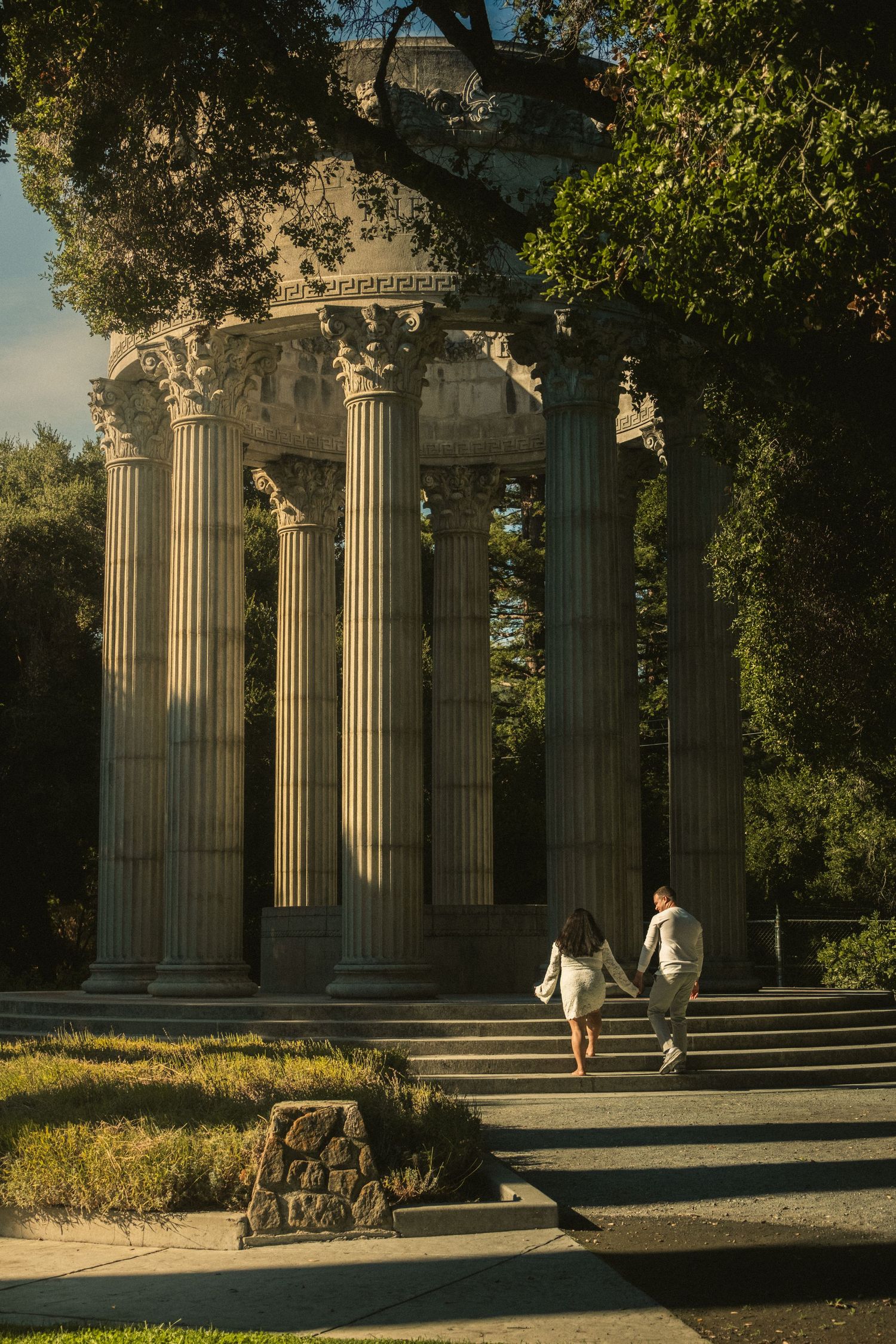 Classical stone columns in a park during golden hour.