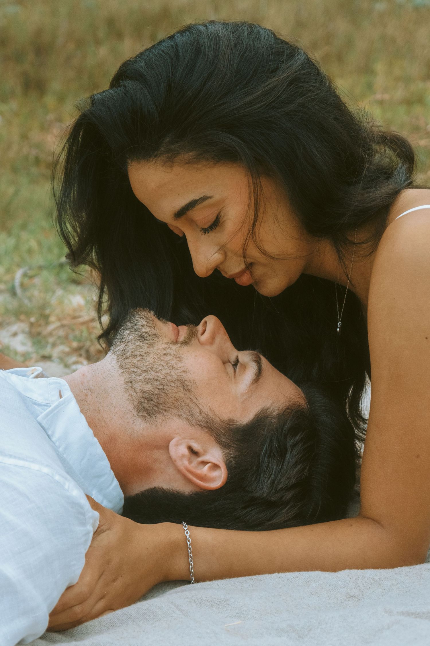 Close-up of an intimate moment between a couple lying down outdoors.