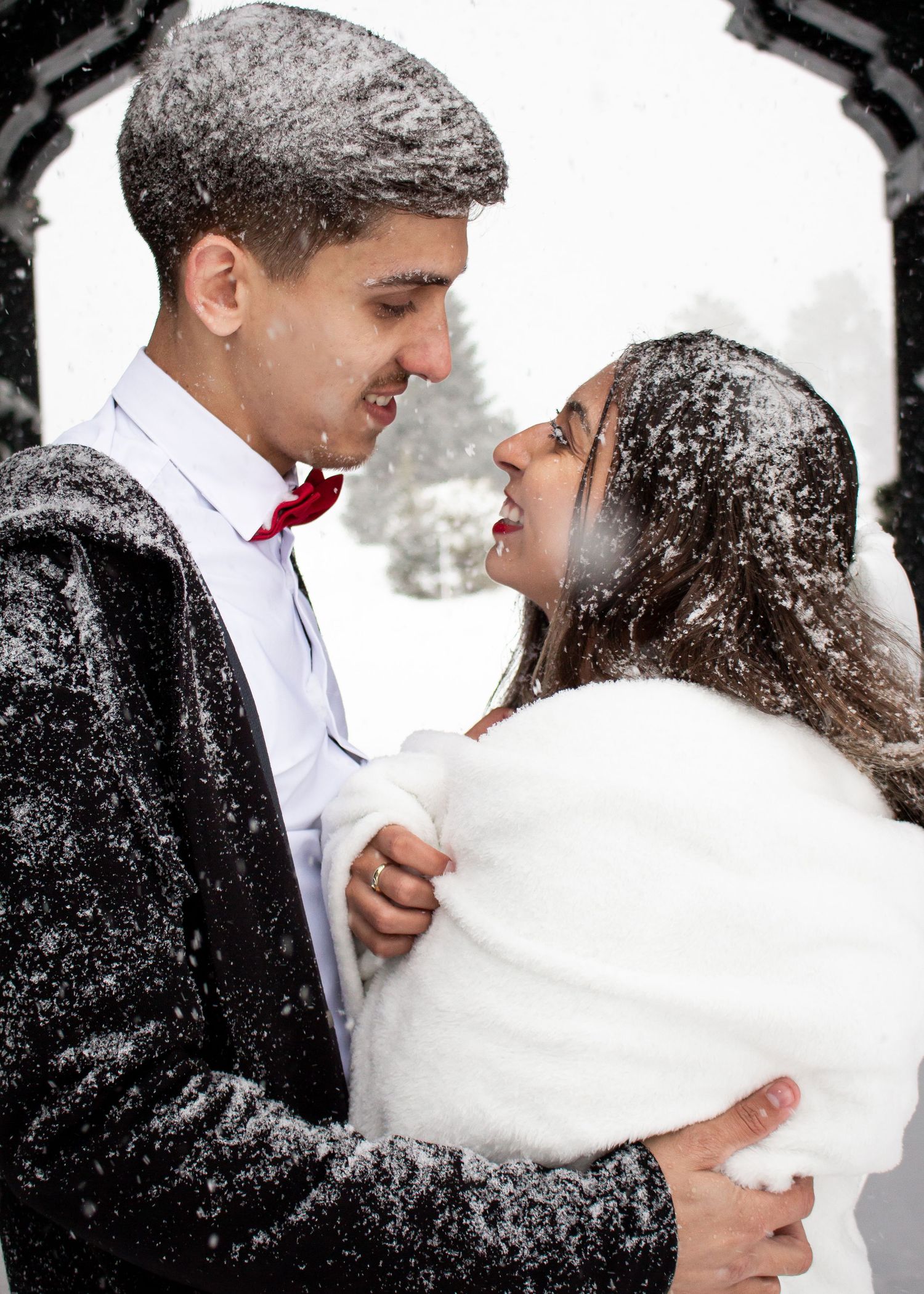 Intimate winter wedding portrait with snowflakes falling around the couple.