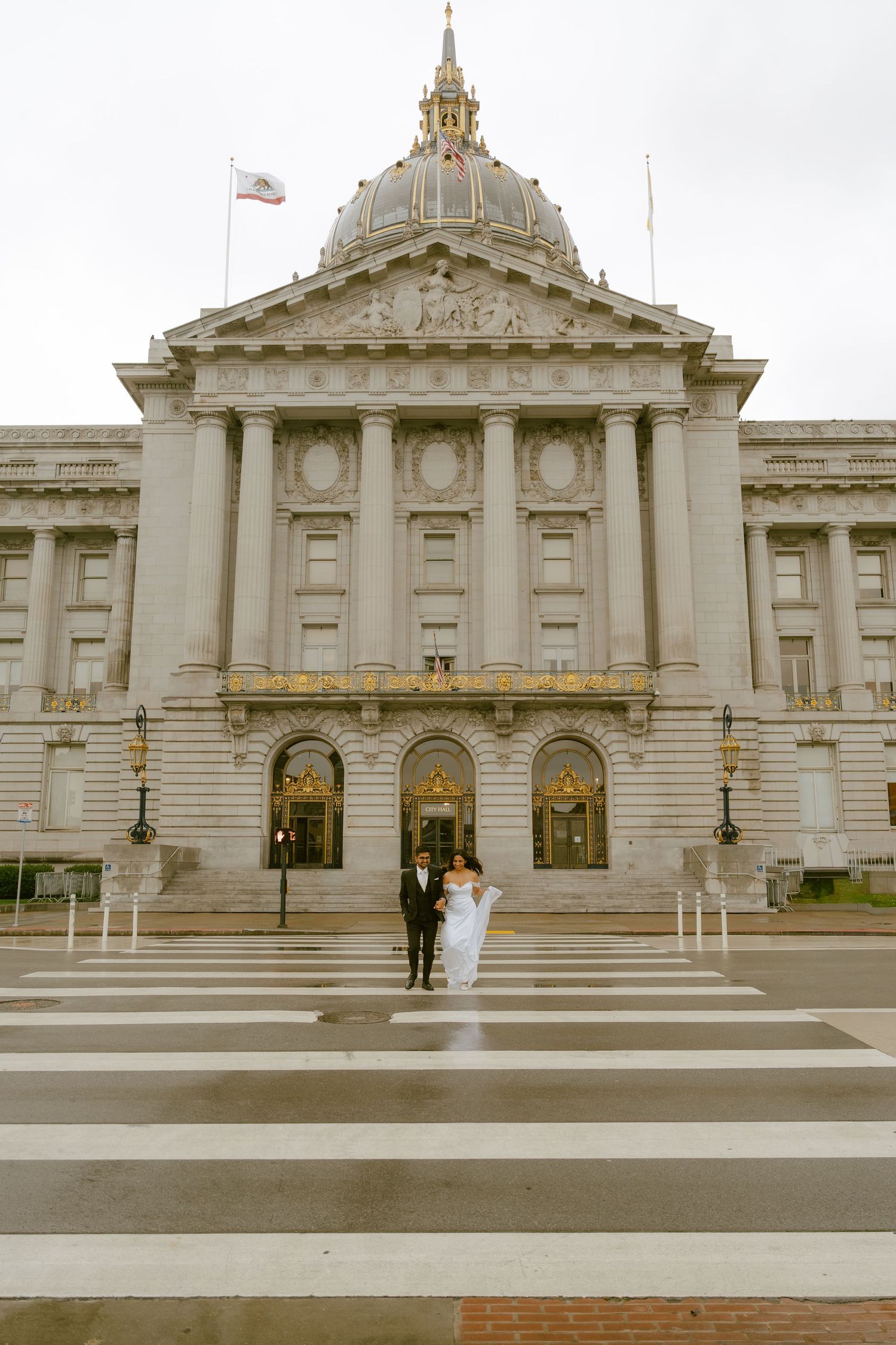 Newlywed couple crossing street in front of San Francisco City Hall on their wedding day.
