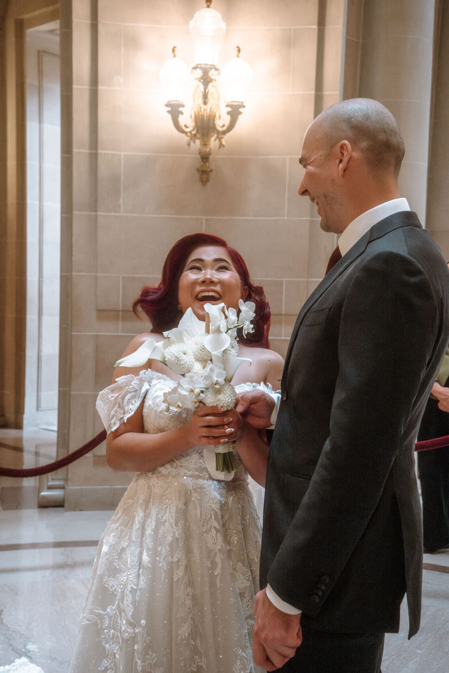 A couple shares a tender moment in an ornate marble hallway.