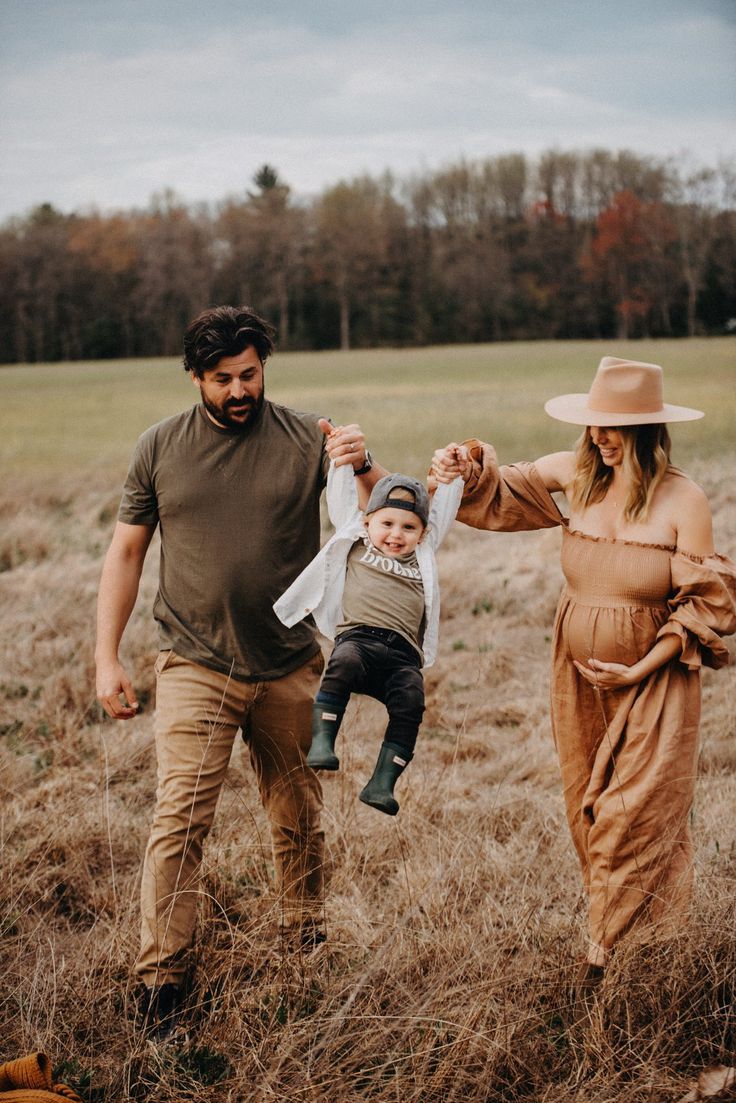 Family playing together in autumn field as parents swing child between them.