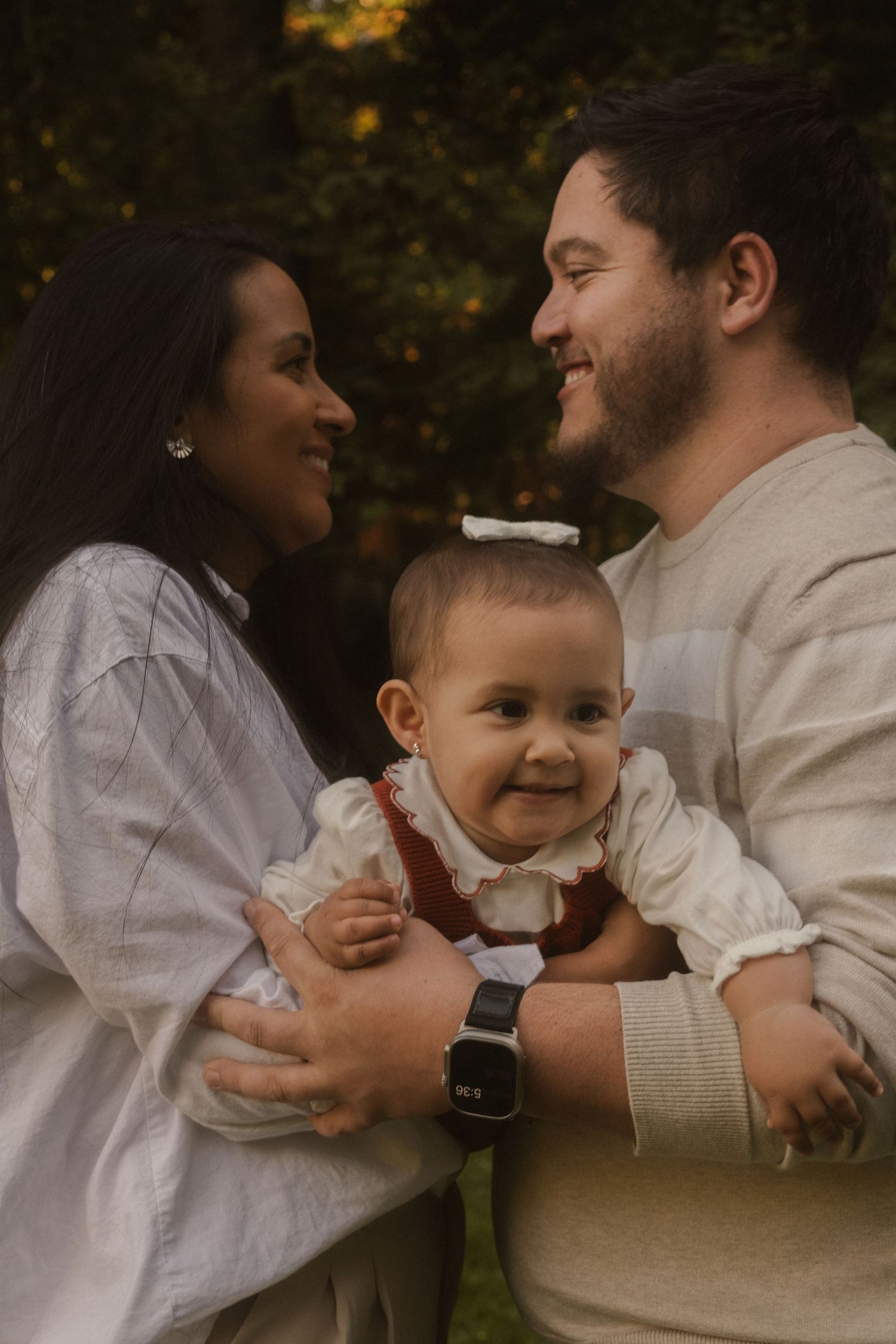 A family shares joyful moments together on a sunny evening in a park setting.