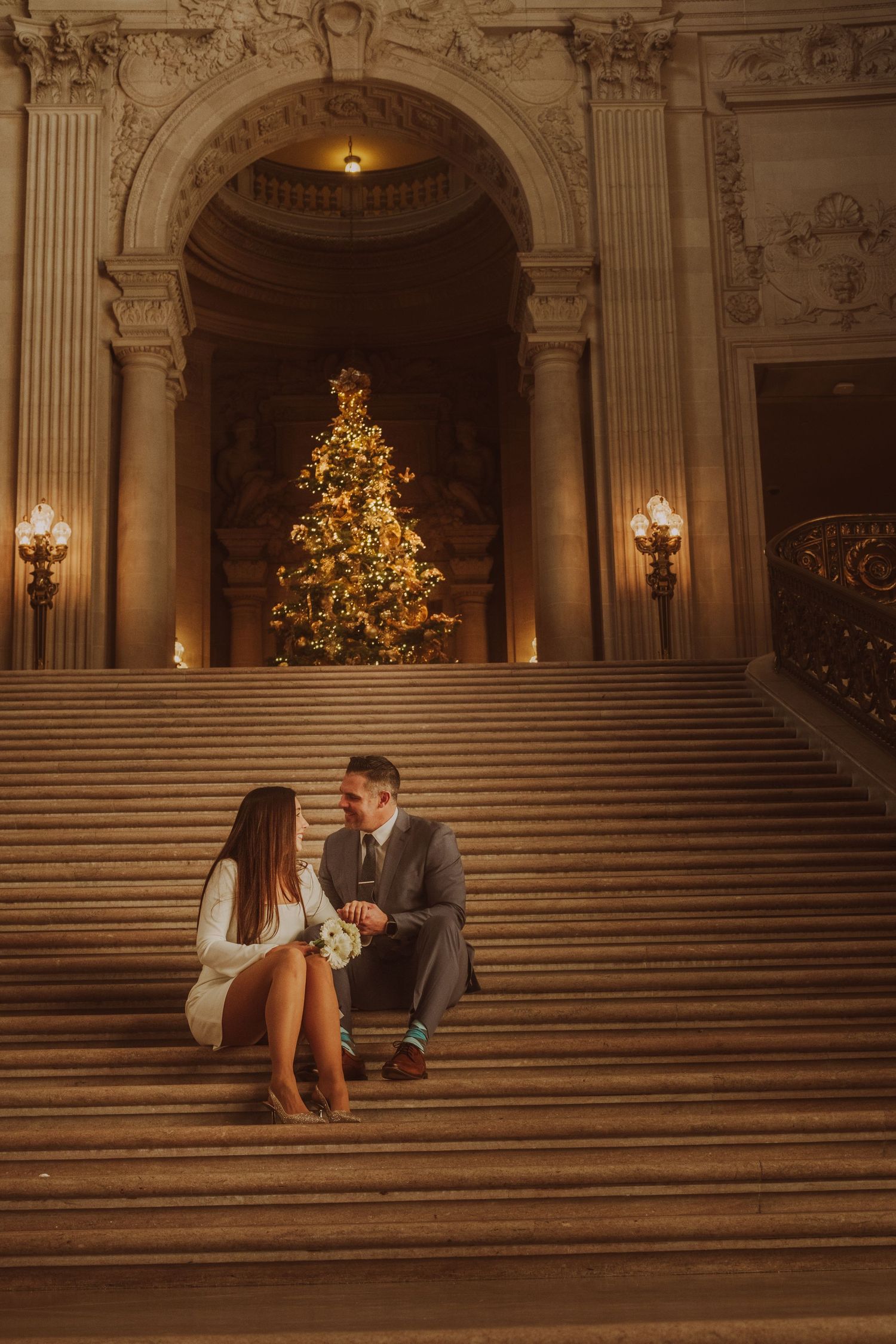 Romantic moment on the grand staircase of City Hall with Christmas tree in background.