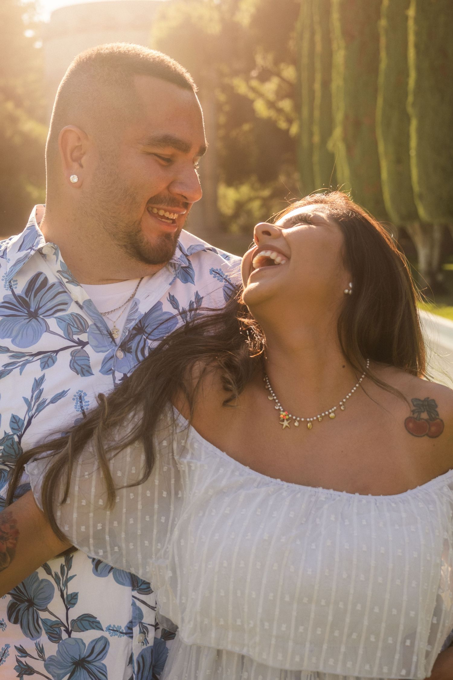 A couple shares an intimate moment in a garden wearing coordinated blue and white outfits.