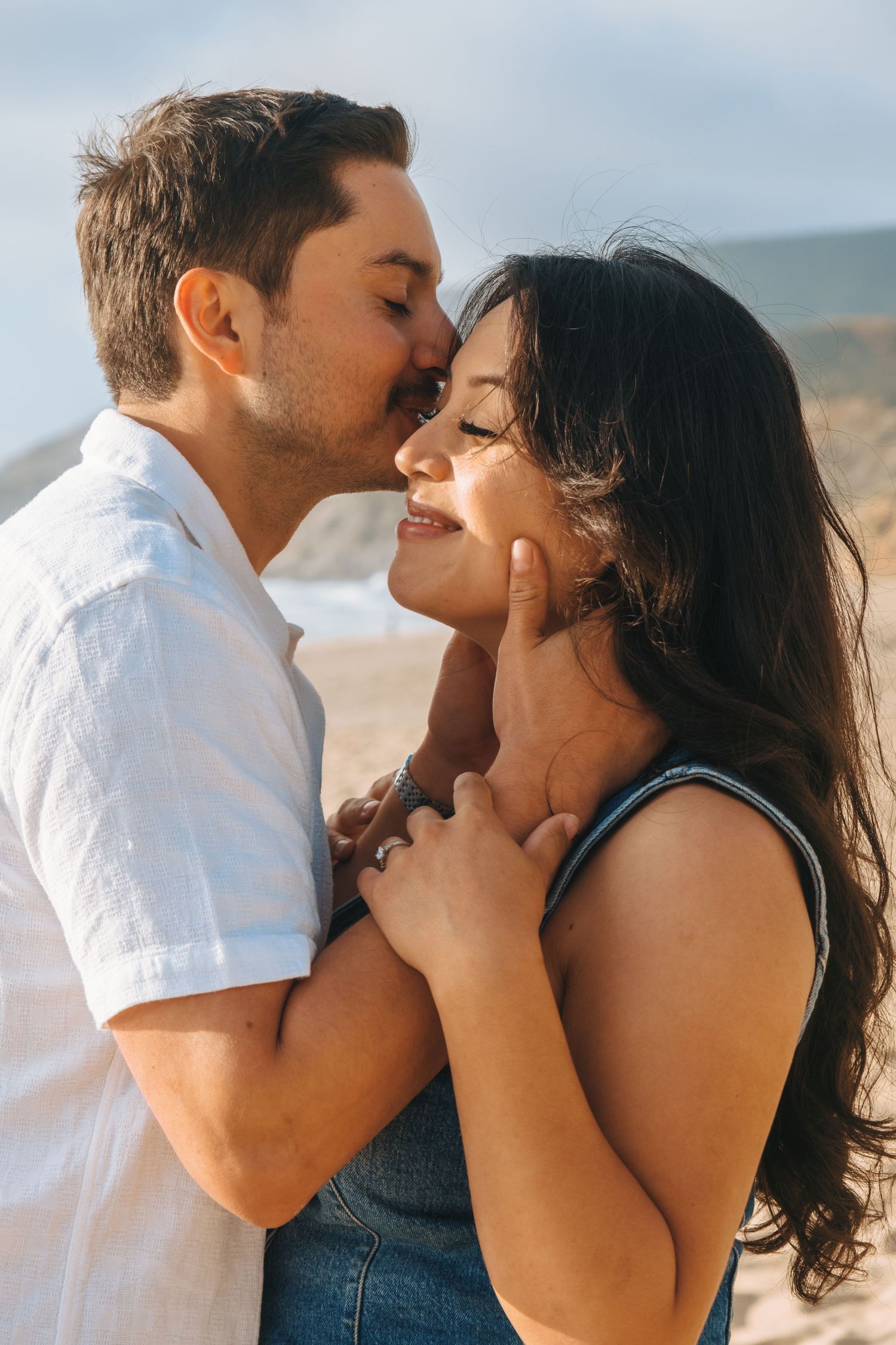A romantic couple shares intimate moments at the beach during sunset.