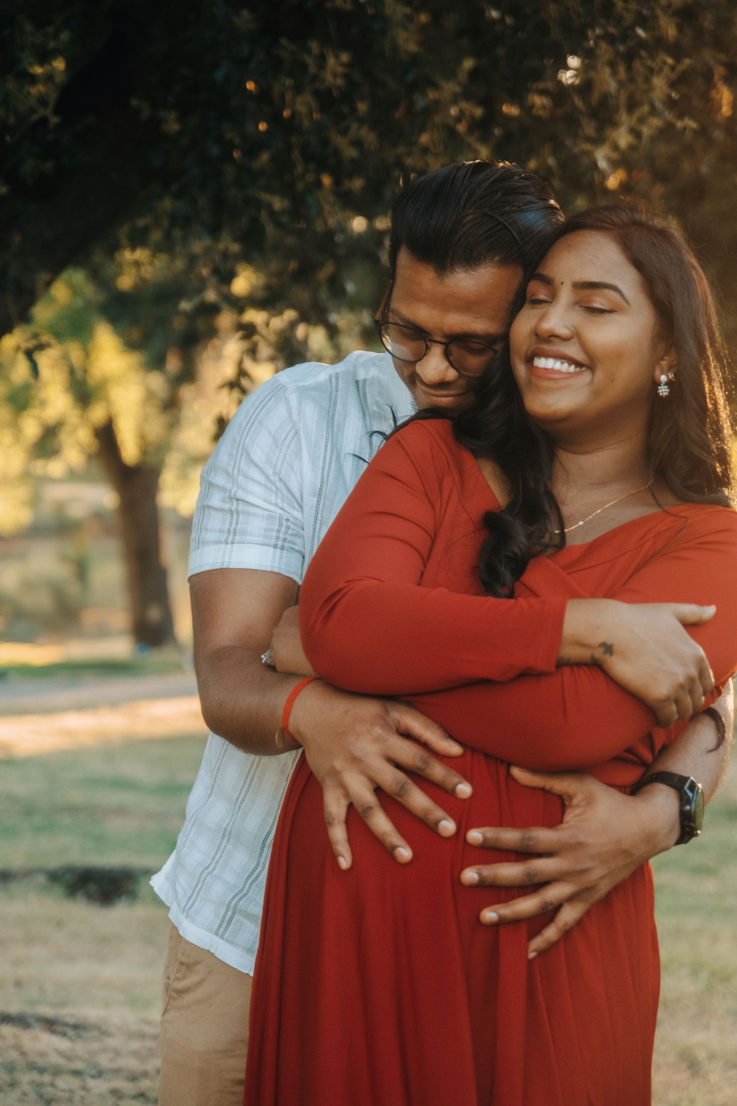Intimate maternity photos of a couple embracing under warm sunset lighting.