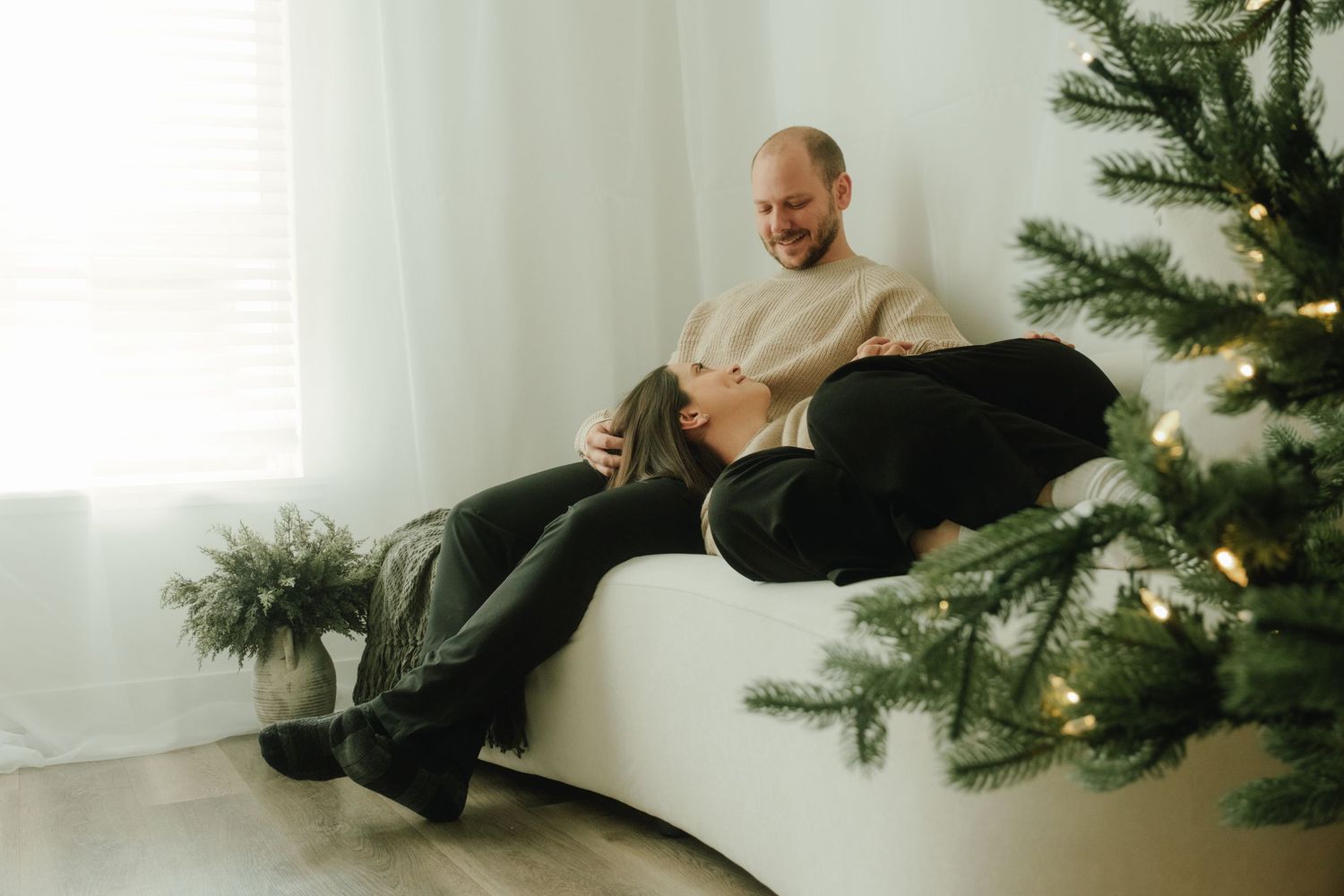 Cozy indoor holiday scene with person lounging near decorated Christmas tree.